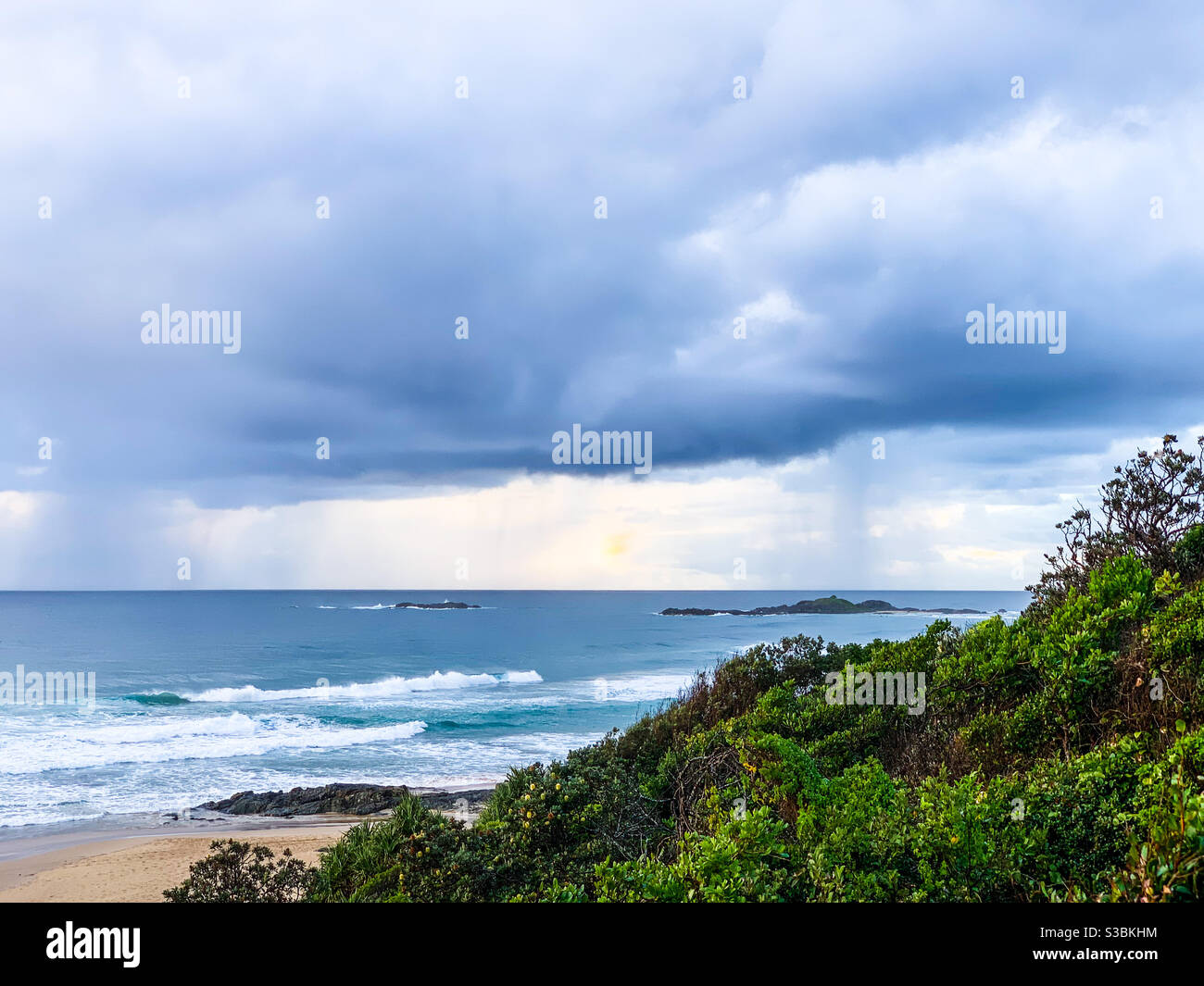 Raining out at sea. Australian landscape, bush, ocean, waves, sandy beach and cloudy sky - Smartphone Captured Stock Image
