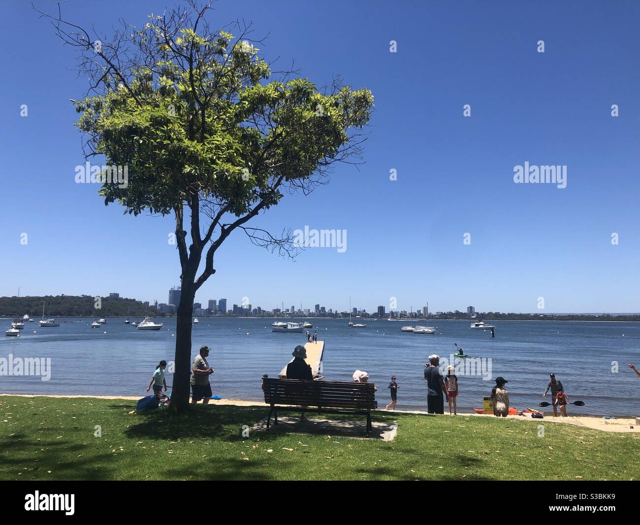 People enjoying a summers day at Matilda Bay Reserve, Crawley Western Australia. The Perth city skyline is in the background across the river. Stock Photo