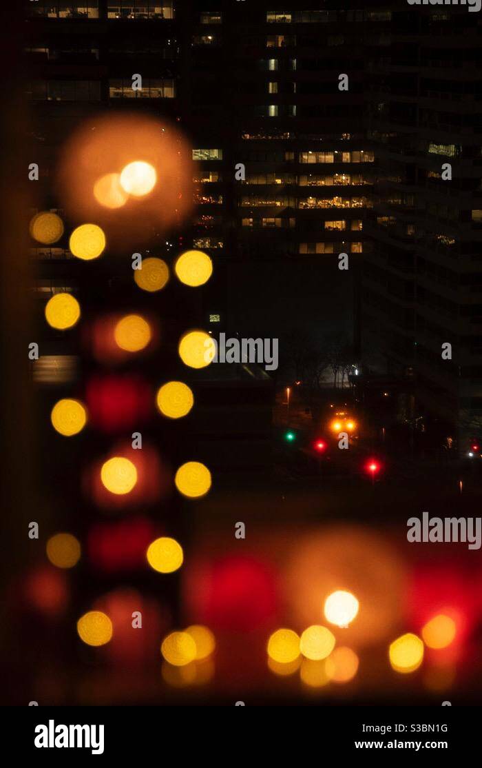 Lonely car on deserted city streets at night framed by holiday lights Stock Photo
