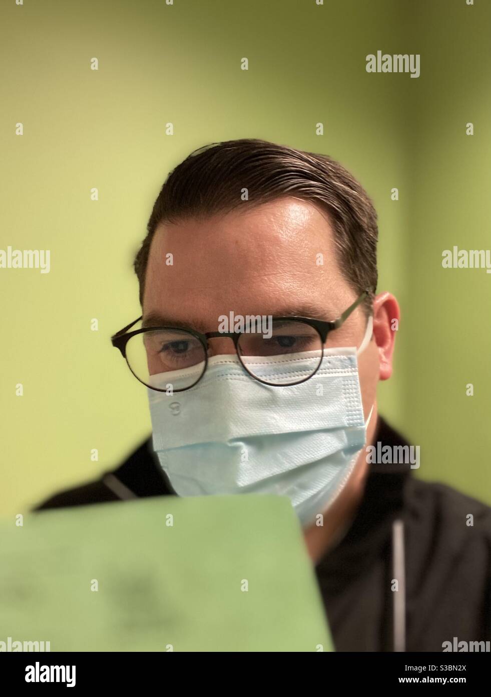 Medical professional examining green documents with green background in medical clinic in