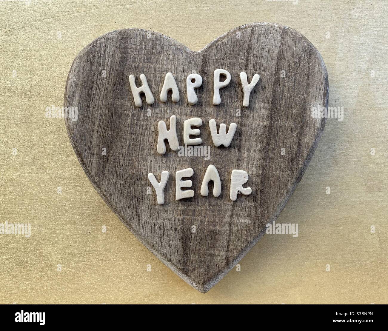 Happy New Year with wooden letters text over a wooden heart Stock Photo