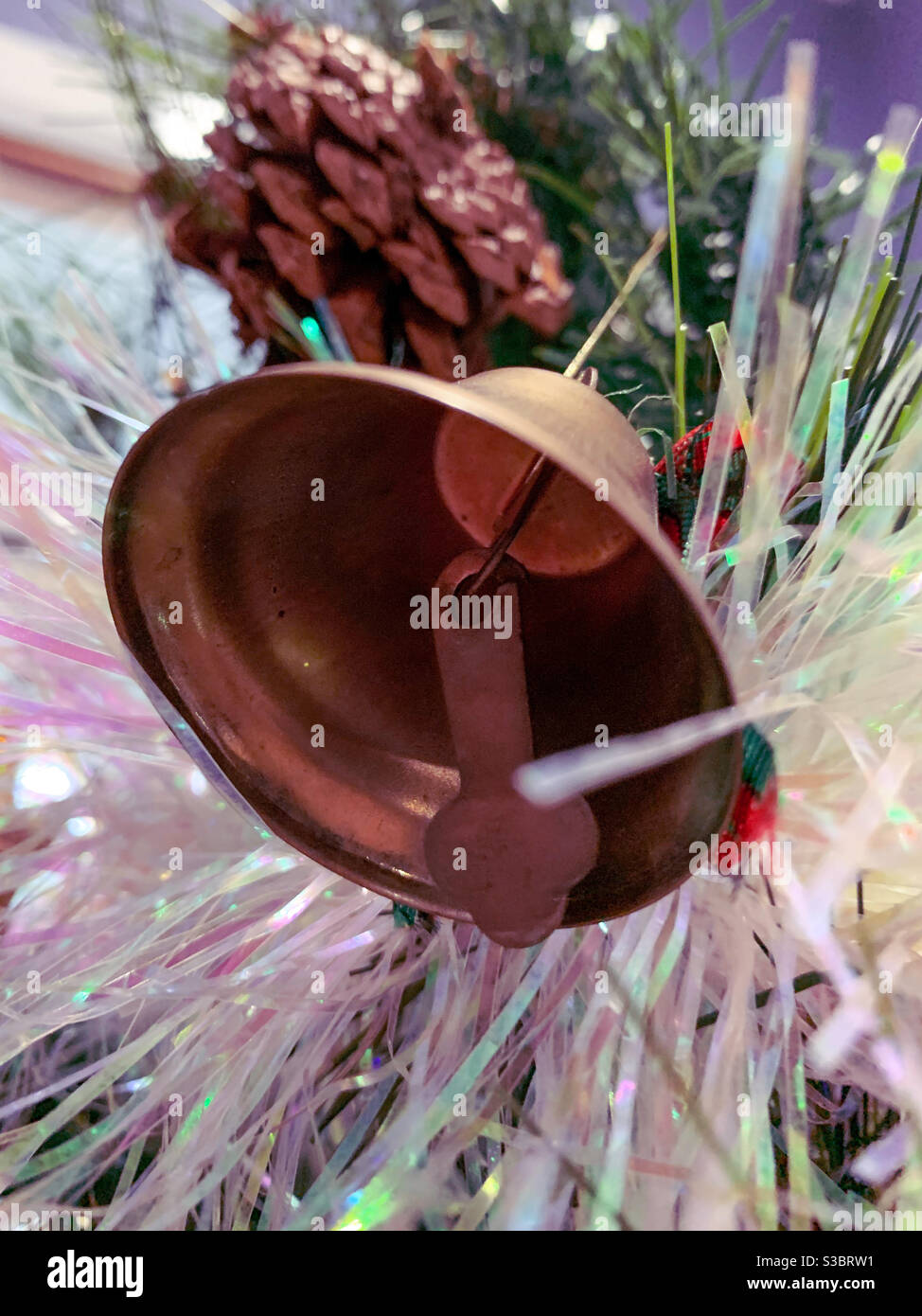 Looking up into a Christmas bell ornament on a tree with tinsel - Smartphone Captured Stock Image