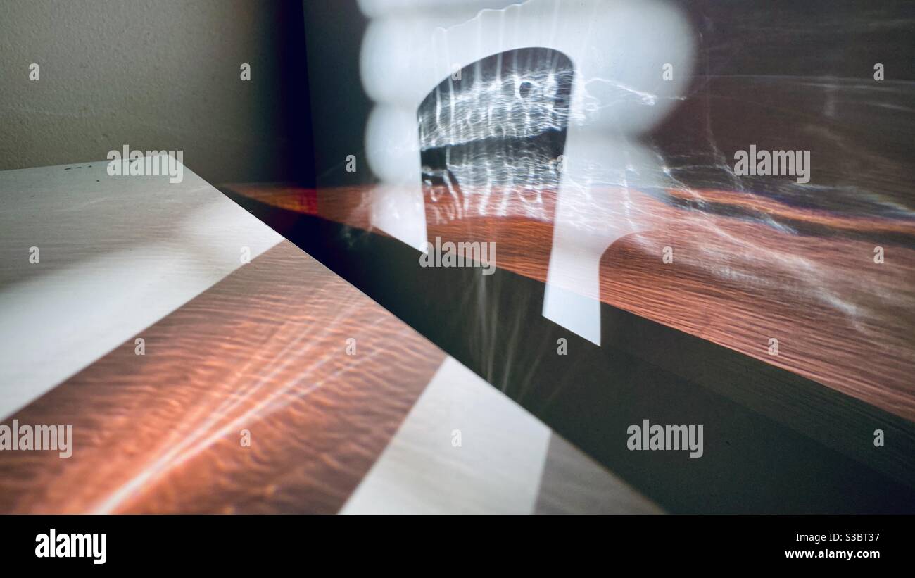 Patterns of light created by sunlight passing through a window blinds and glass of red liquid, refracting across white table and wall to create abstract background - Smartphone Captured Stock Image Patterns of light created by sunlight passing through a window blinds and glass of red liquid, refracting across white table and wall to create abstract background - Smartphone Captured Stock Image