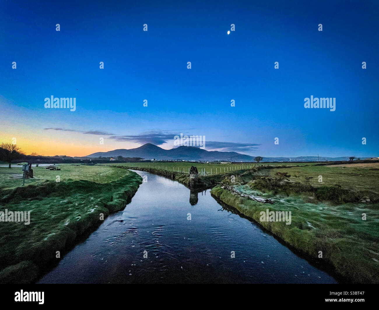 Slieve Donard at sunrise moon still up with river in foreground Stock Photo