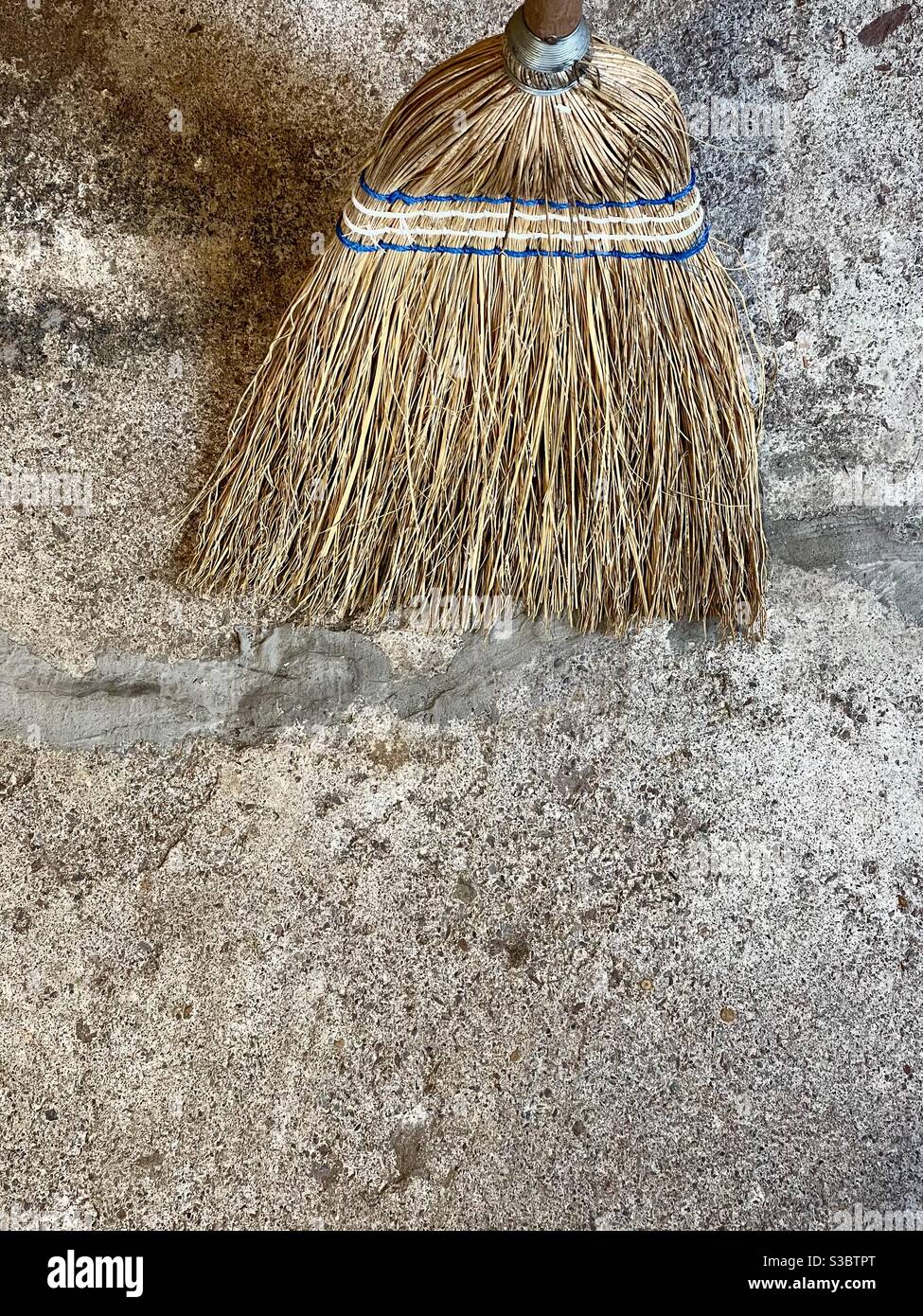 Straw broom on a clean concrete floor. Stock Photo