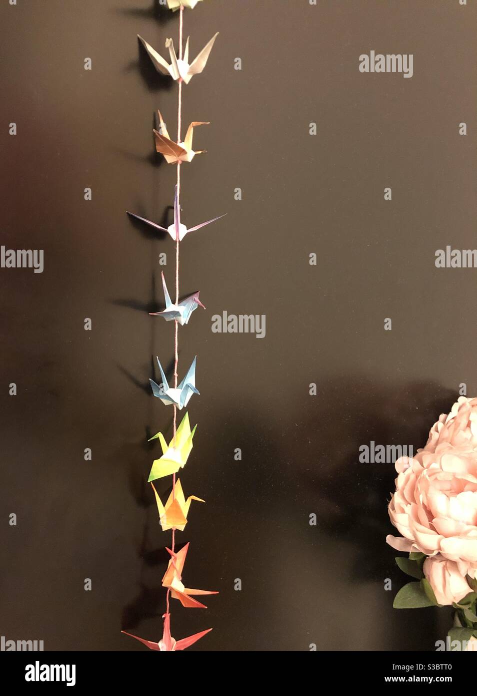 String of origami paper cranes with pink flower Stock Photo Alamy