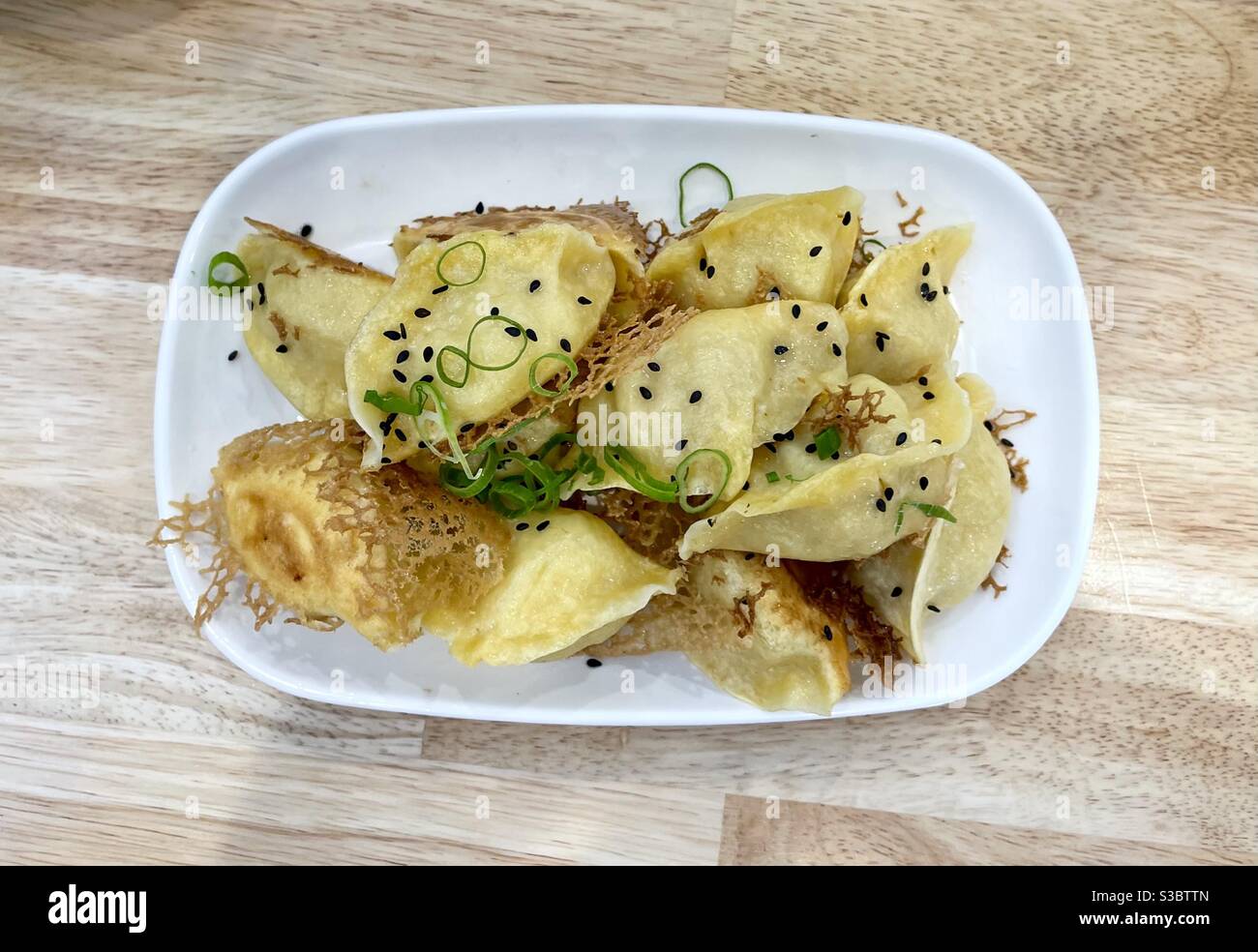 Pan fried chicken and prawn dumplings garnished with black sesame seeds