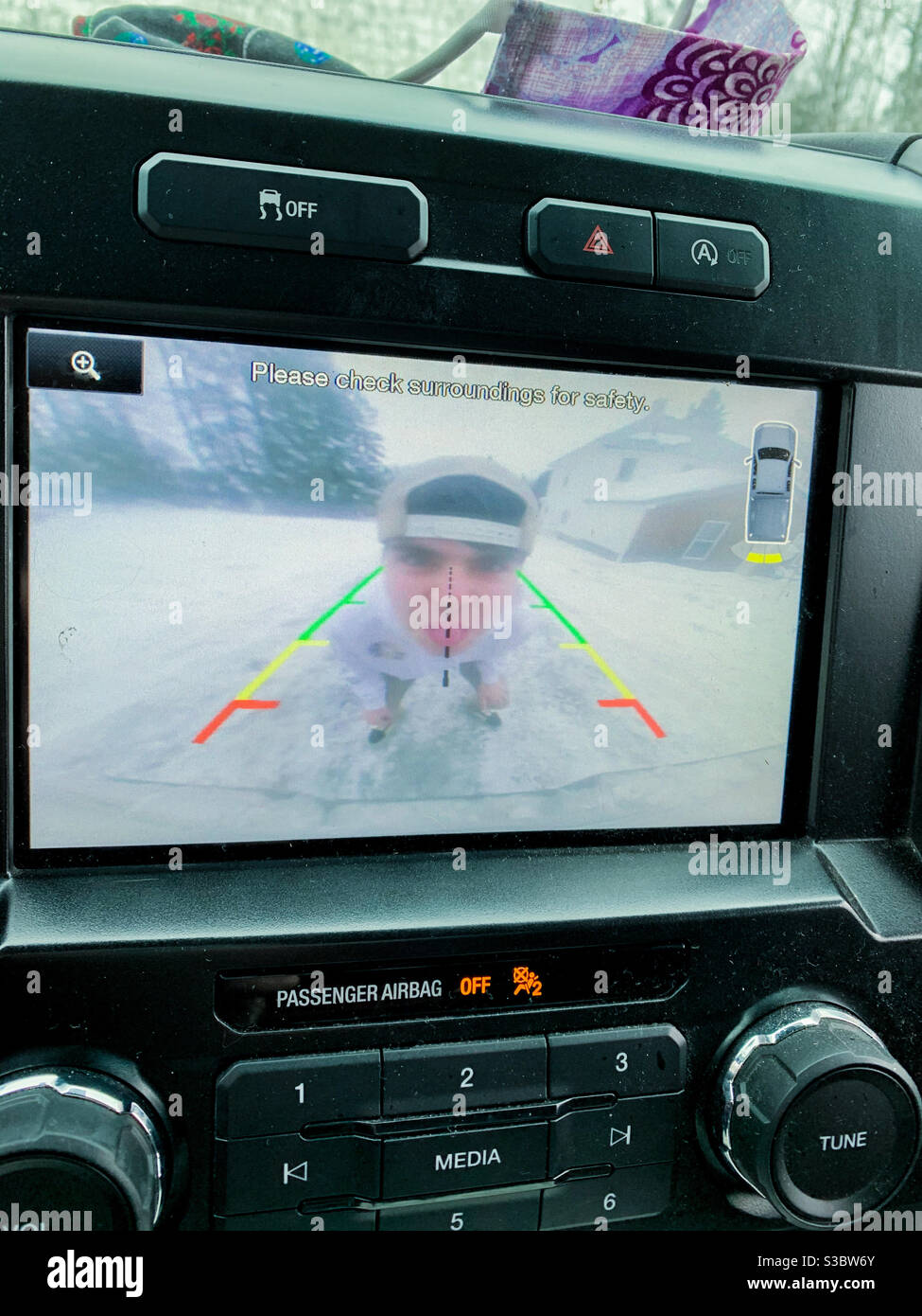 A teenager sticking out his tongue after cleaning off the backup camera. - Smartphone Captured Stock Image