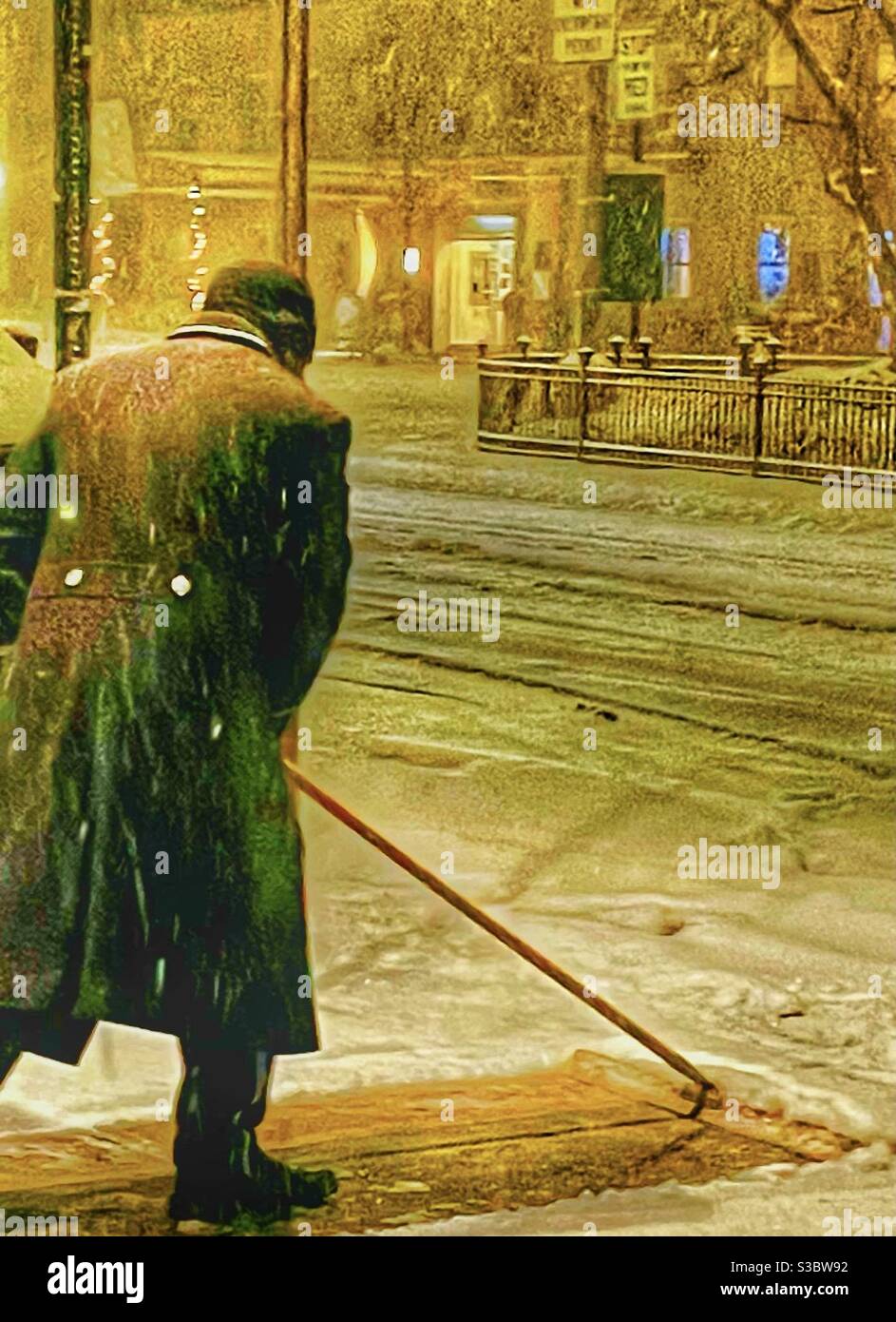 The night  doorman at 30 Park Avenue in New York City clears the sidewalk of slippery snow during a snowstorm. Stock Photo