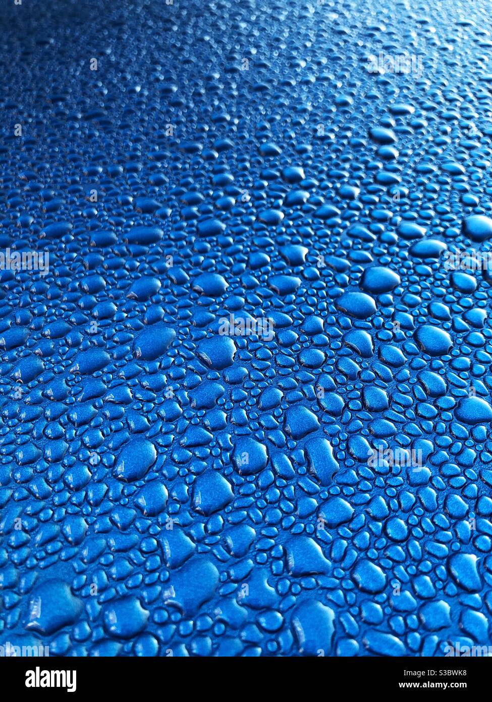 Condensation water droplets on a shiny blue metallic surface in a cold temperature background - Smartphone Captured Stock Image