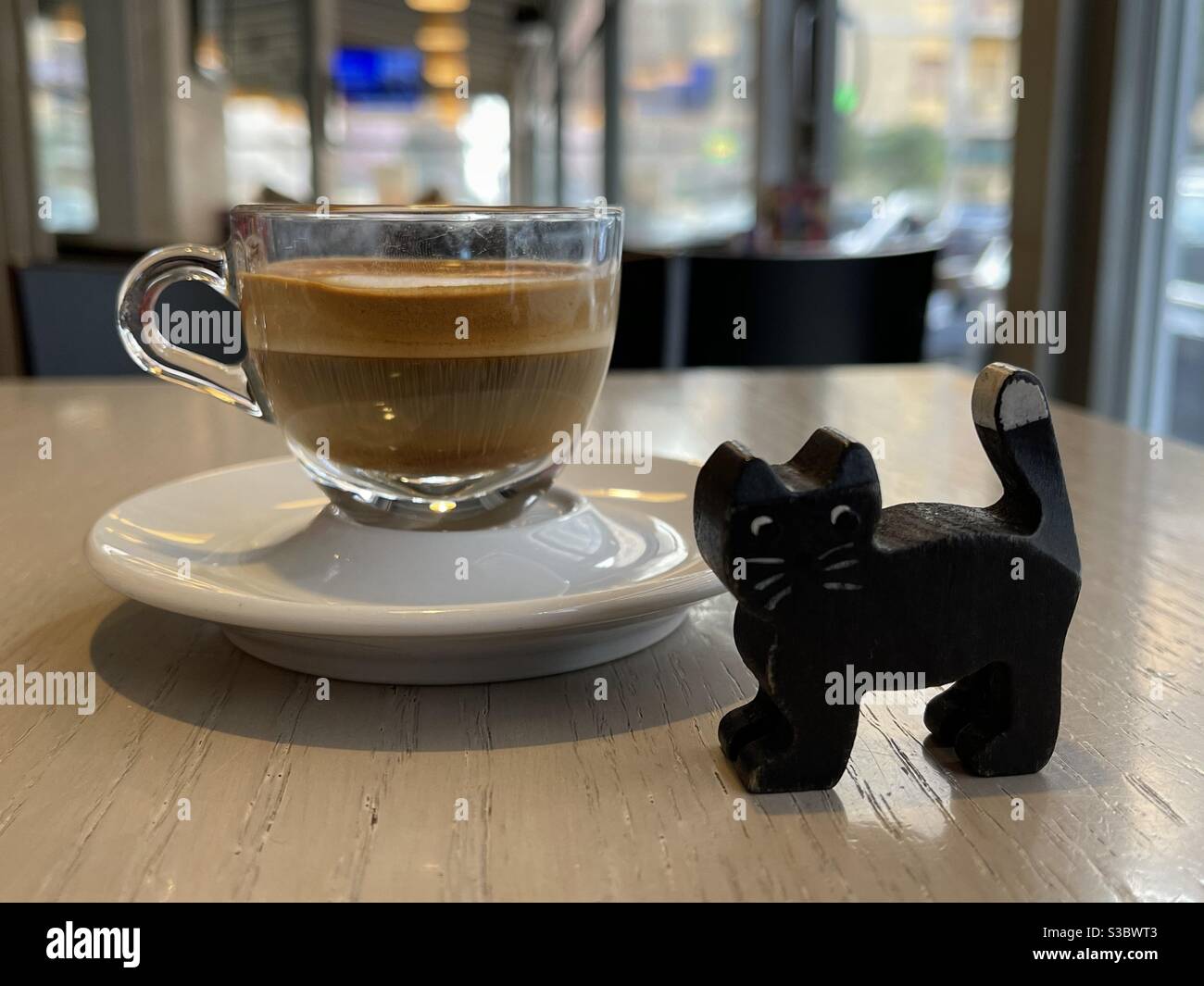 Coffee break with black cat toy at the bar Stock Photo