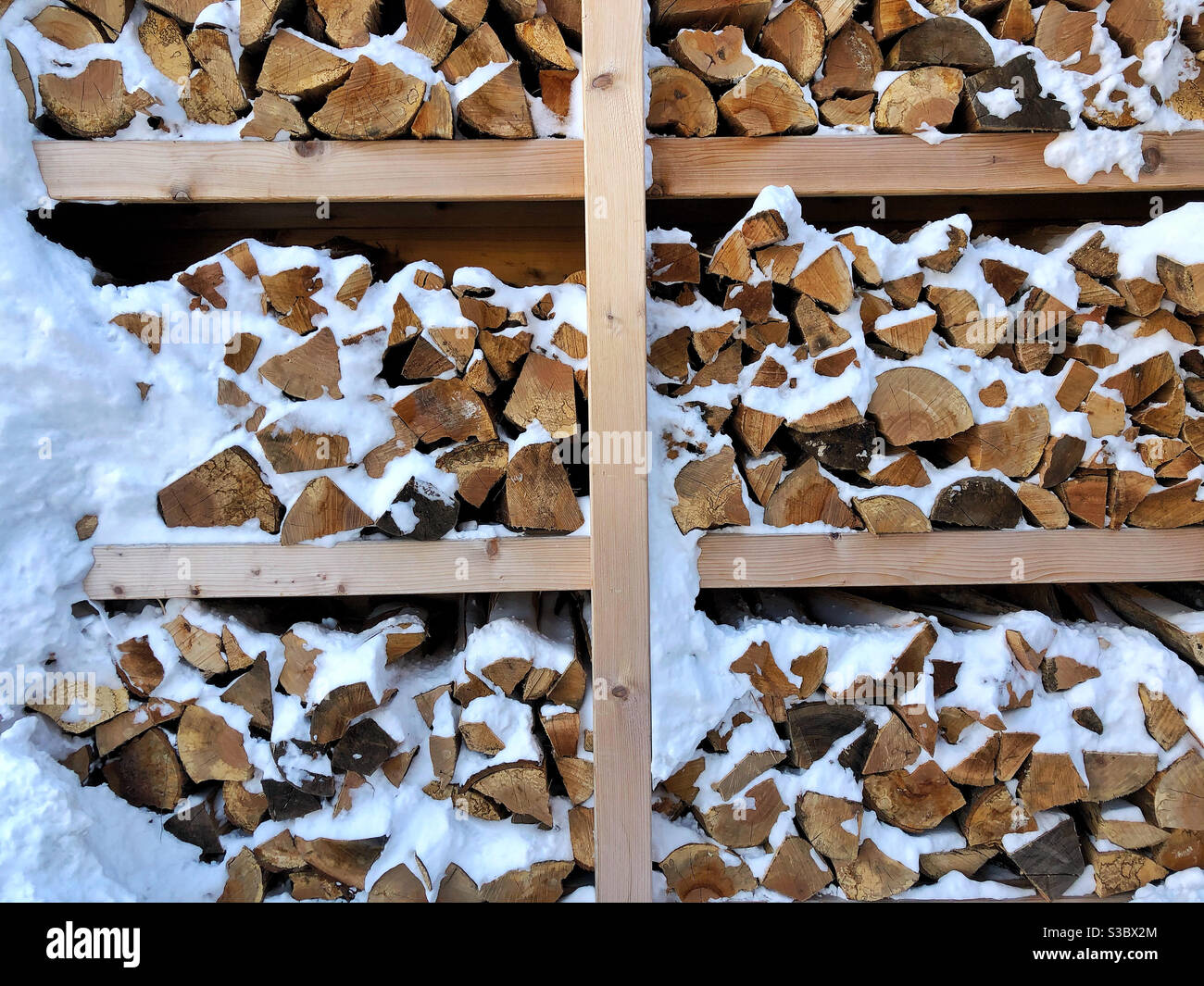 Fresh snow on stacked and cut firewood Stock Photo