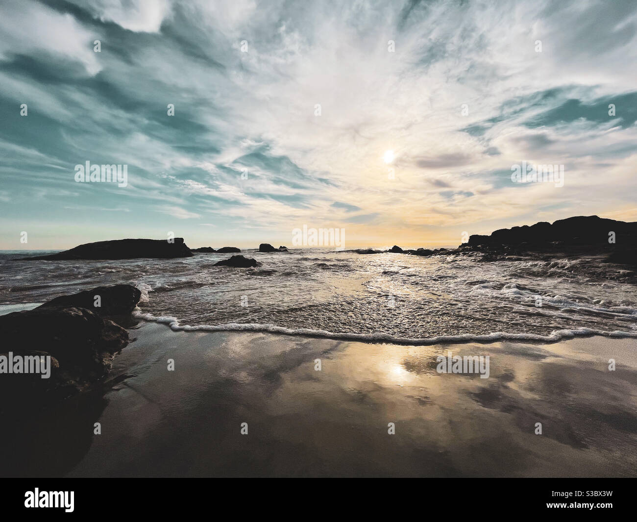 Dramatic sky over sandy beach with gentle wave slowly moving in. - Smartphone Captured Stock Image