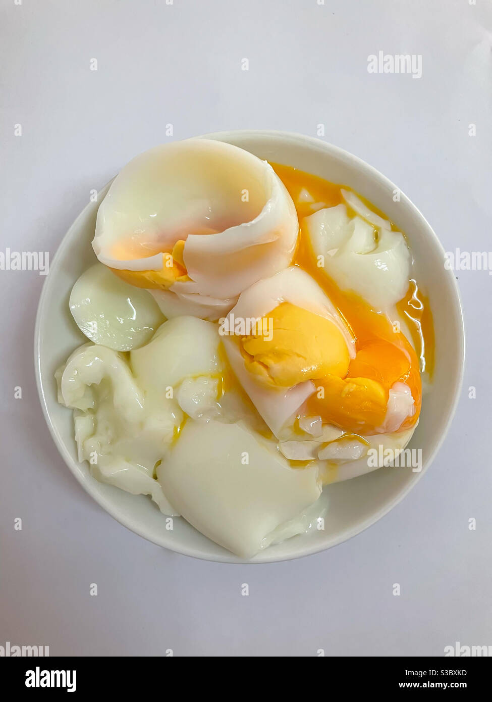Half boiled eggs served in a small white bowl. Stock Photo