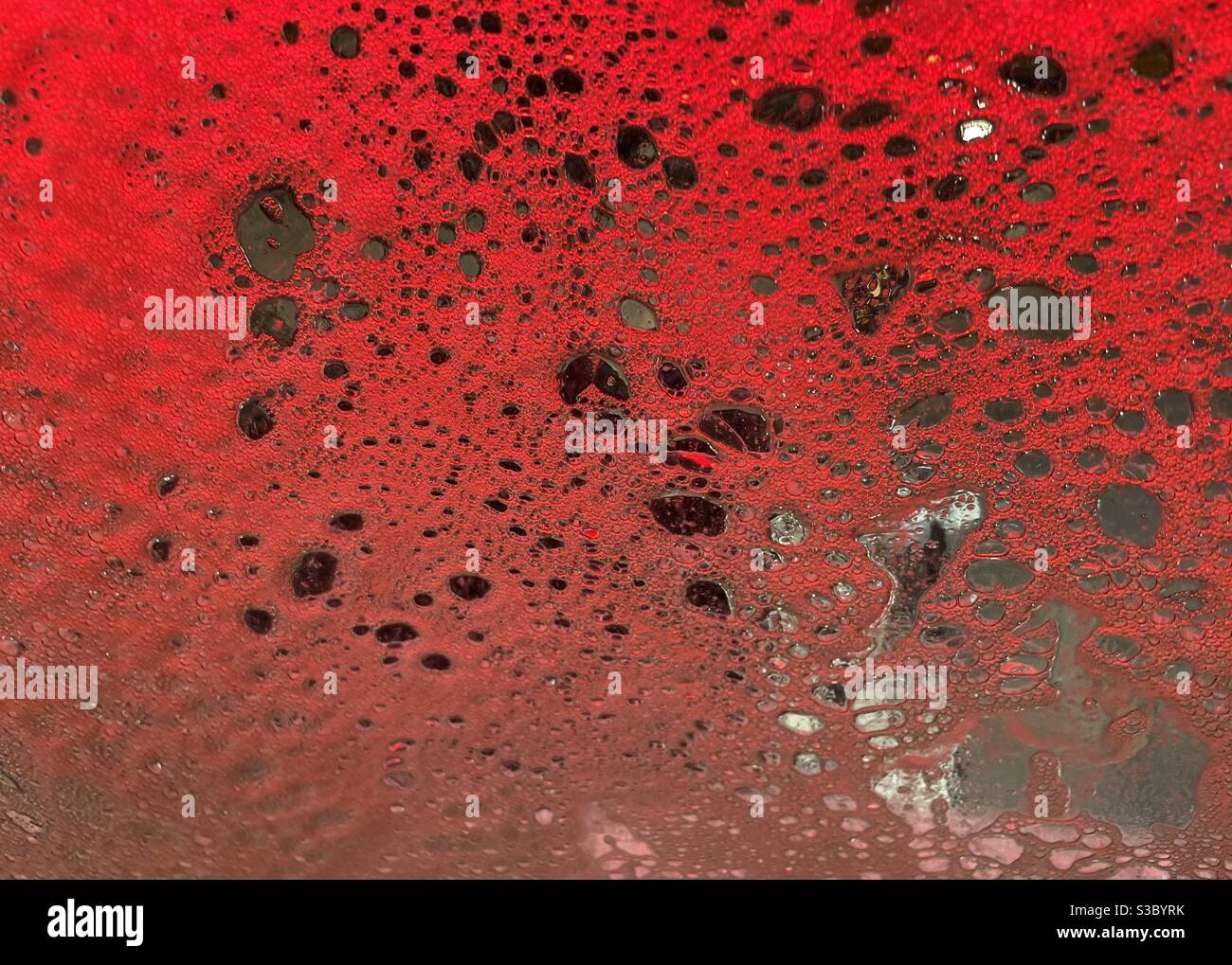 Abstract background of red soapy suds on a car windshield Stock Photo