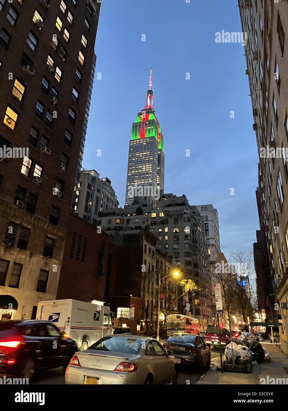 Evening street scene in New York City featuring the Empire State building with Christmas green and red and white lights - Smartphone Captured Stock Image