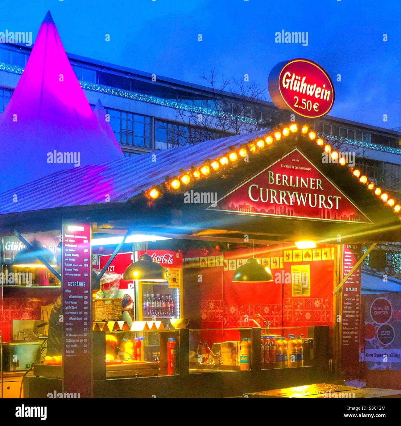 The Christmas market in Berlin Germany features food stalls with delicious specialties like Berliner Currywurst and gluhwein. Currywurst is a hot dog with spicy sauce & gluhwein is hot mulled wine. Stock Photo