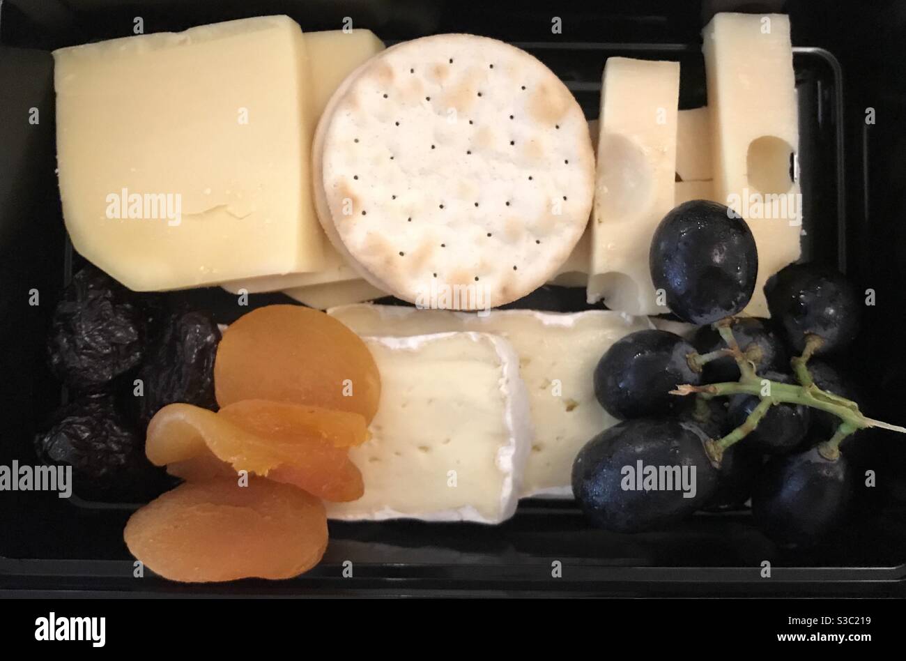 Closeup image of a breakfast cheese platter served with fresh grapes and dried fruit - Smartphone Captured Stock Image