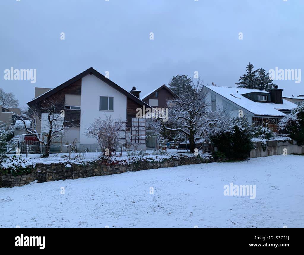 Family houses with saddle roofs under snow coverage in Switzerland village during twilight. Stock Photo