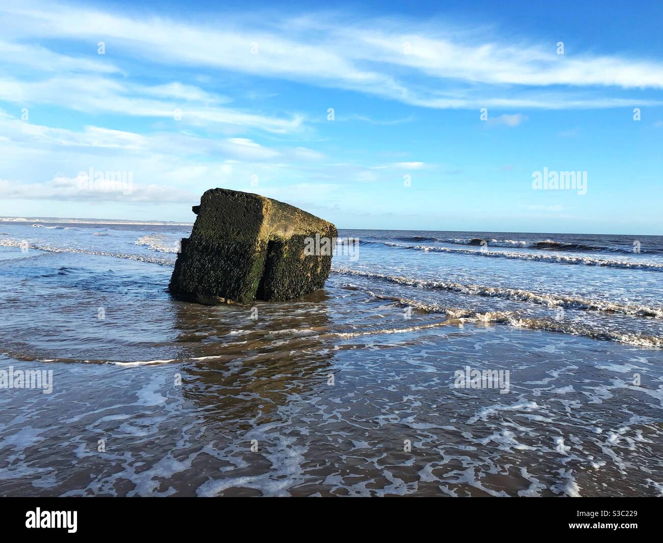 A Military pill box surrounded by the tides of the ocean defending beaches from invading armies - Smartphone Captured Stock Image