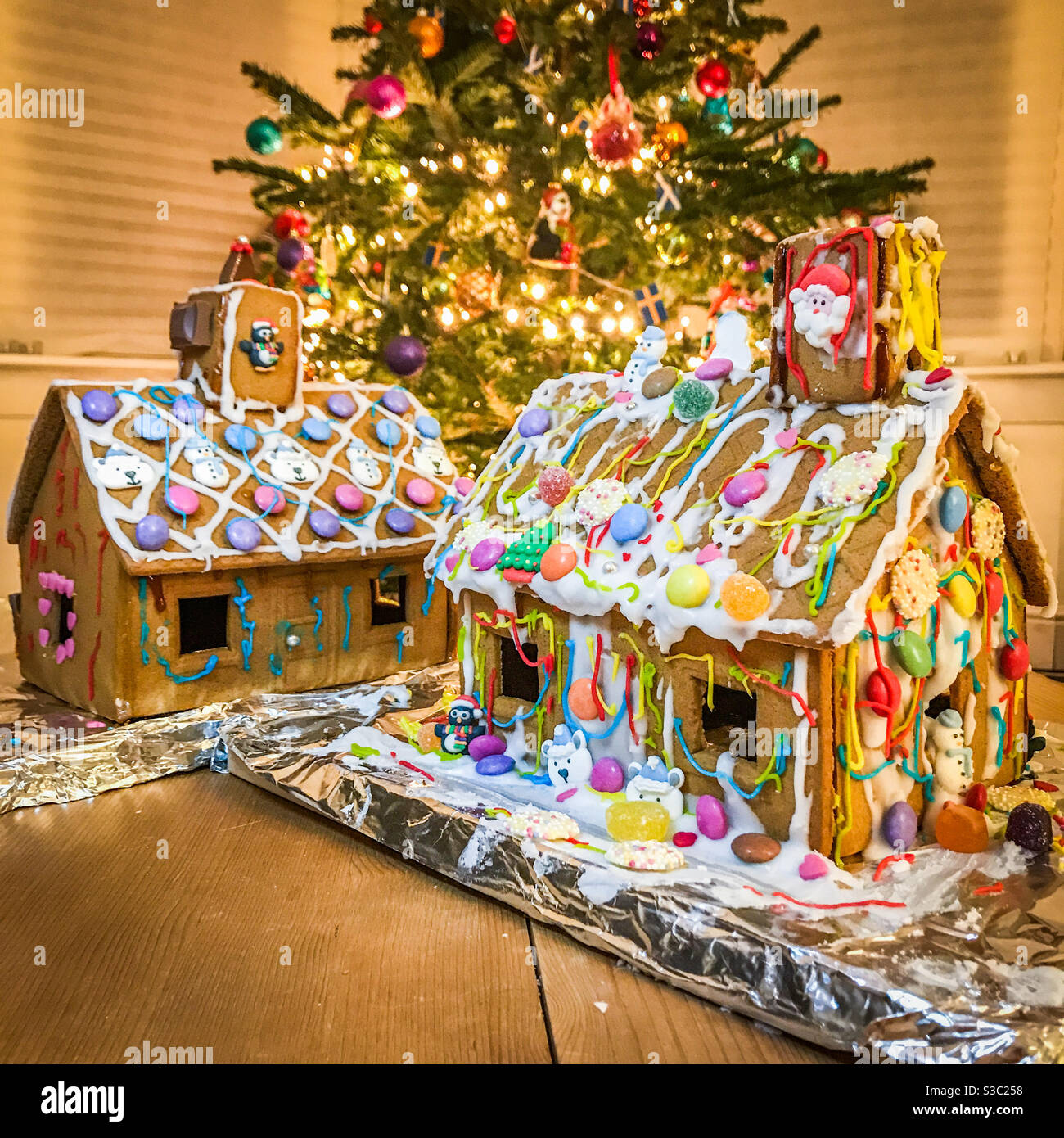 Two gingerbread houses in front of a Christmas tree - Smartphone Captured Stock Image