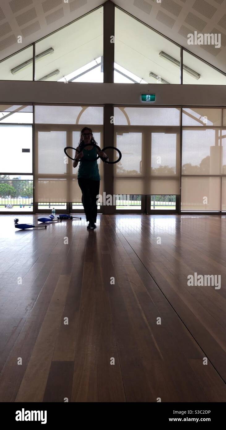 Circus performer in silhouette holding juggling rings with juggling clubs at her feet Stock