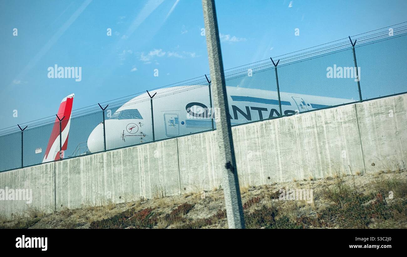 LOS ANGELES, CA, AUG 2020: front of Qantas owned Boeing 747 jet airliner seen through a fence, over wall at Los Angeles International Airport - Smartphone Captured Stock Image