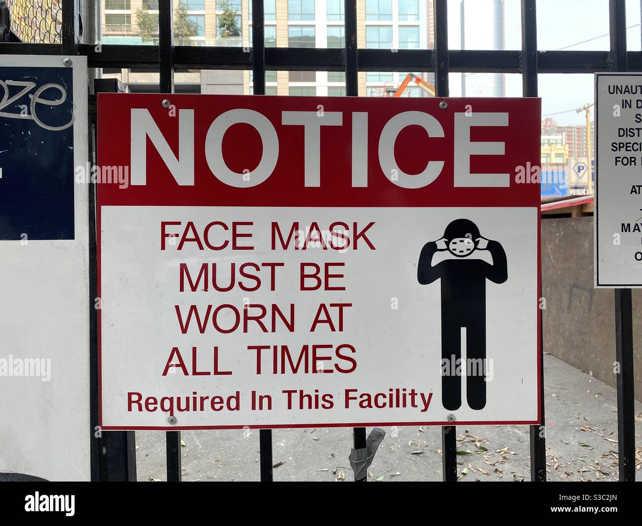LOS ANGELES, CA, OCT 2020: close up on 'face mask must be worn' sign on fence at a construction site during coronavirus pandemic in Downtown - Smartphone Captured Stock Image