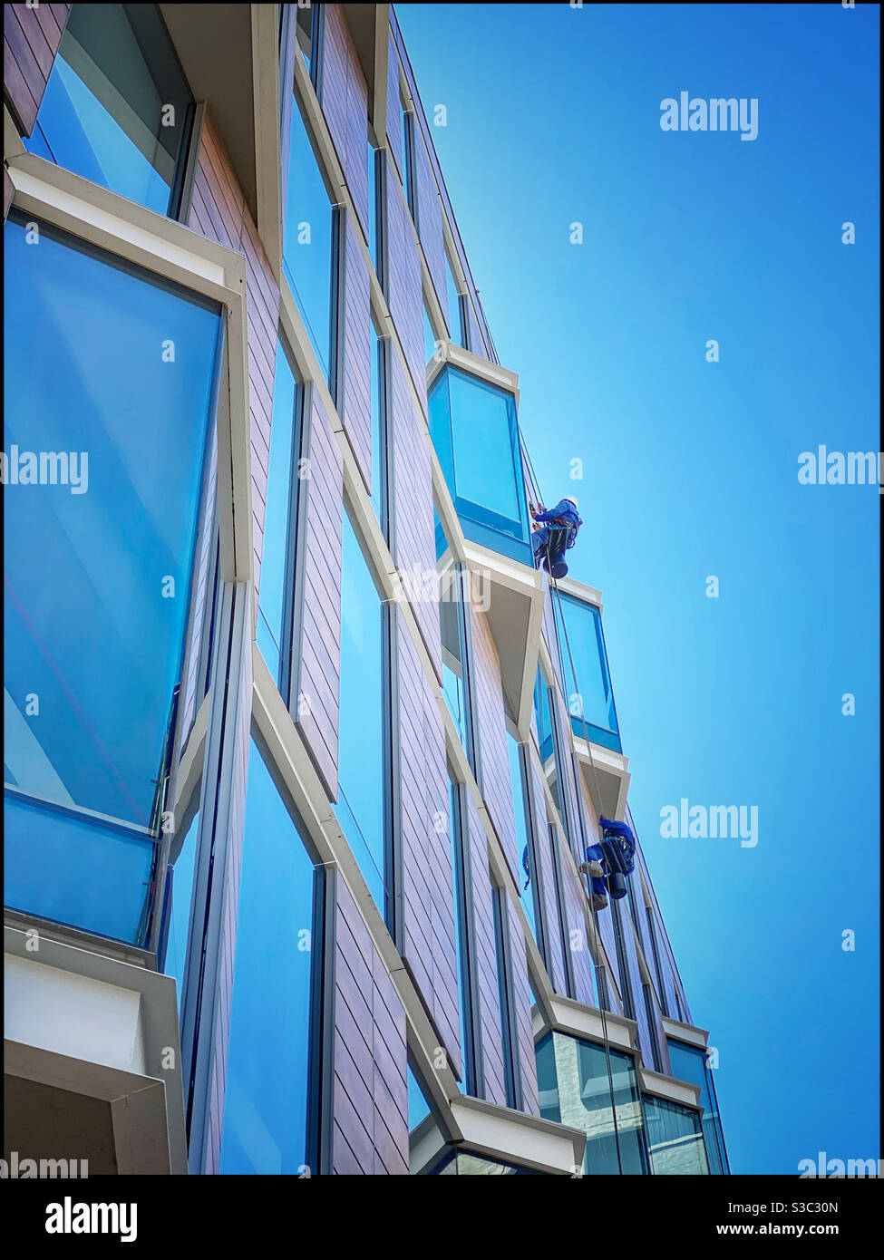 Window cleaners busy Cleaning in Silo district of the V&A Waterfront, Cape Town, South Africa. Stock Photo