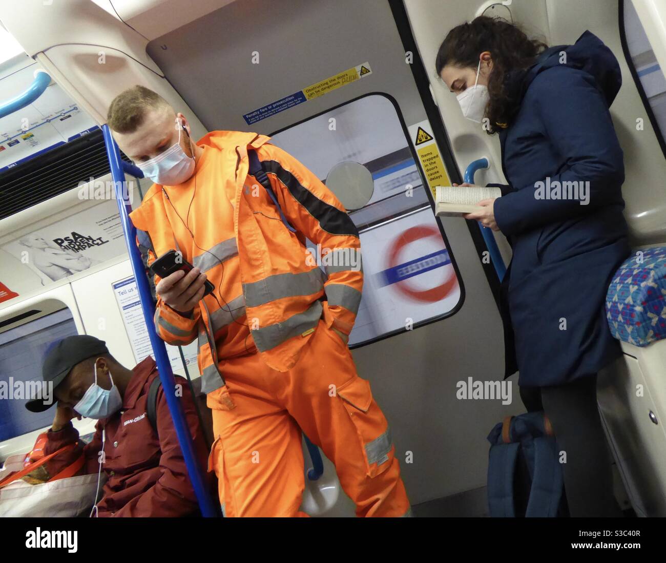 PASSENGERS ON LONDON UNDERGROUND TRAIN WEARING FACE MASKS Stock Photo
