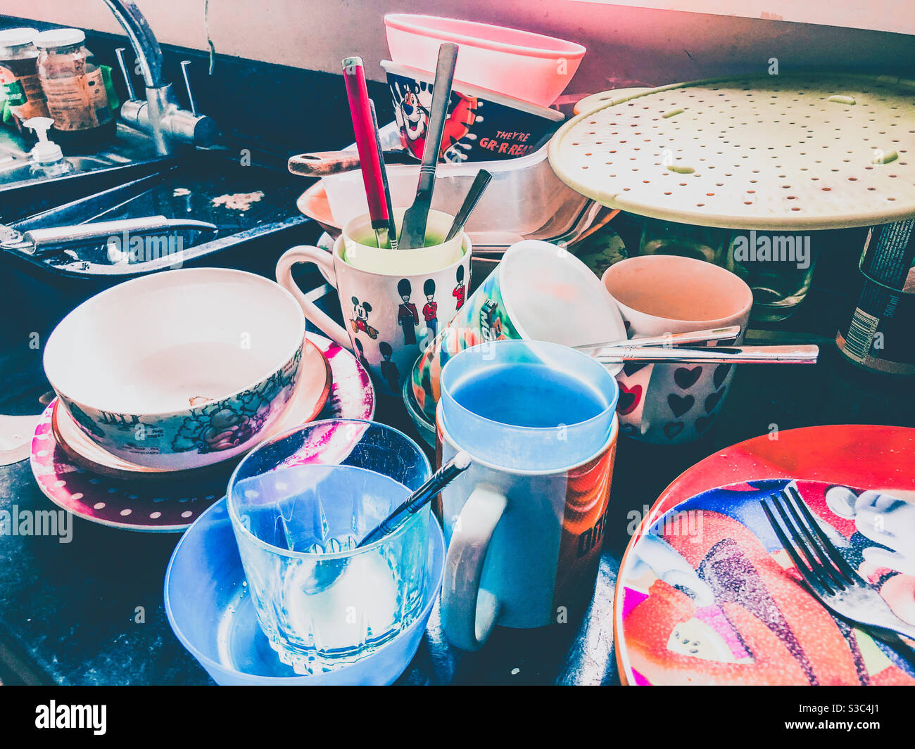 Piles of dirty washing up next to a kitchen sink. - Smartphone Captured Stock Image