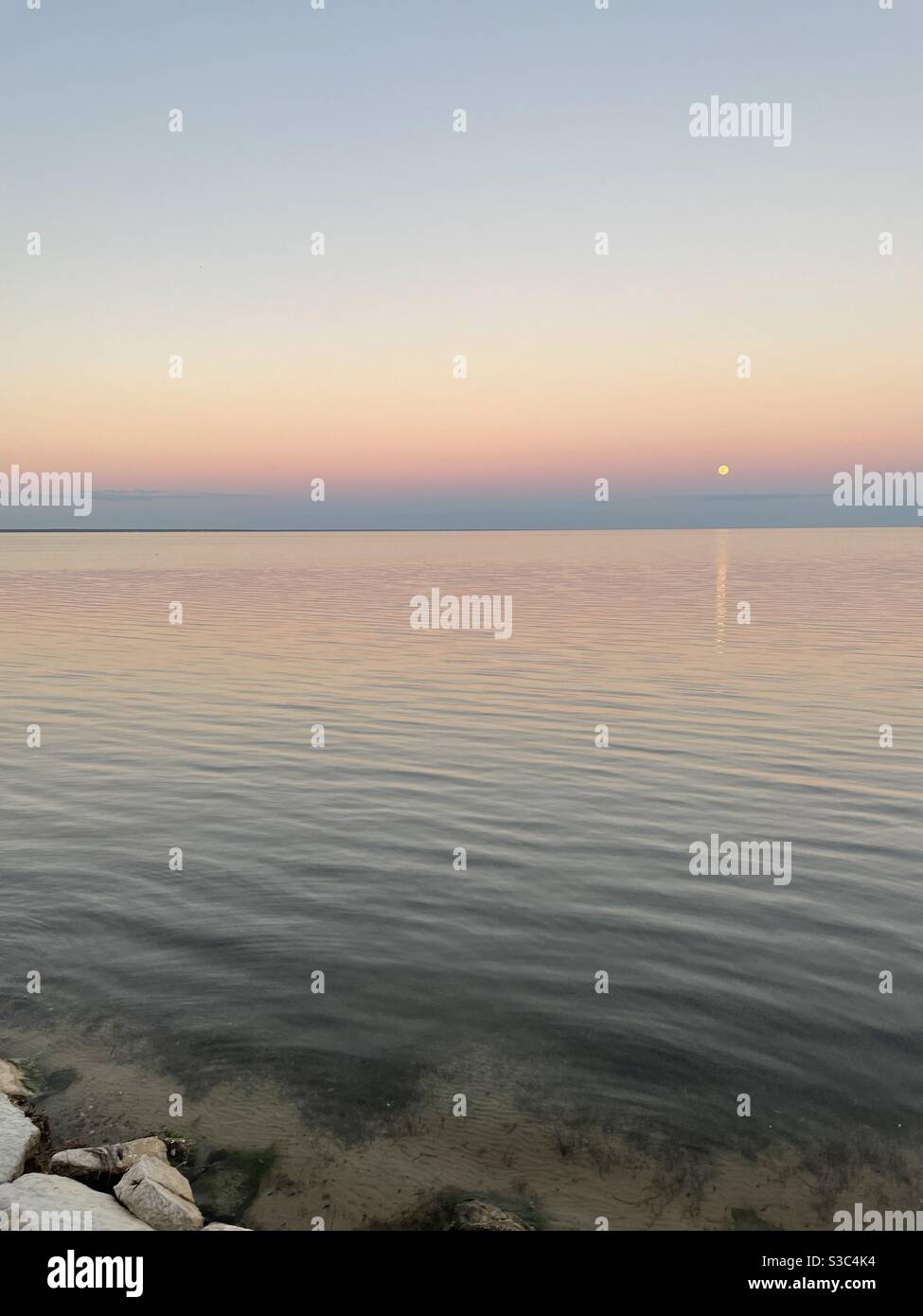 Last full moon of 2020 with sunset skies over bay water - Smartphone Captured Stock Image