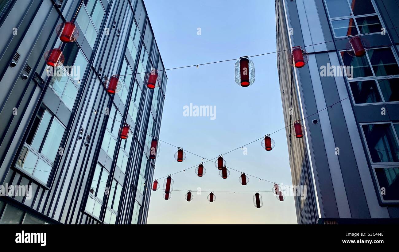 Red lanterns strung between modern buildings in China Town, Los Angeles, looking up into sky at magic hour - Smartphone Captured Stock Image