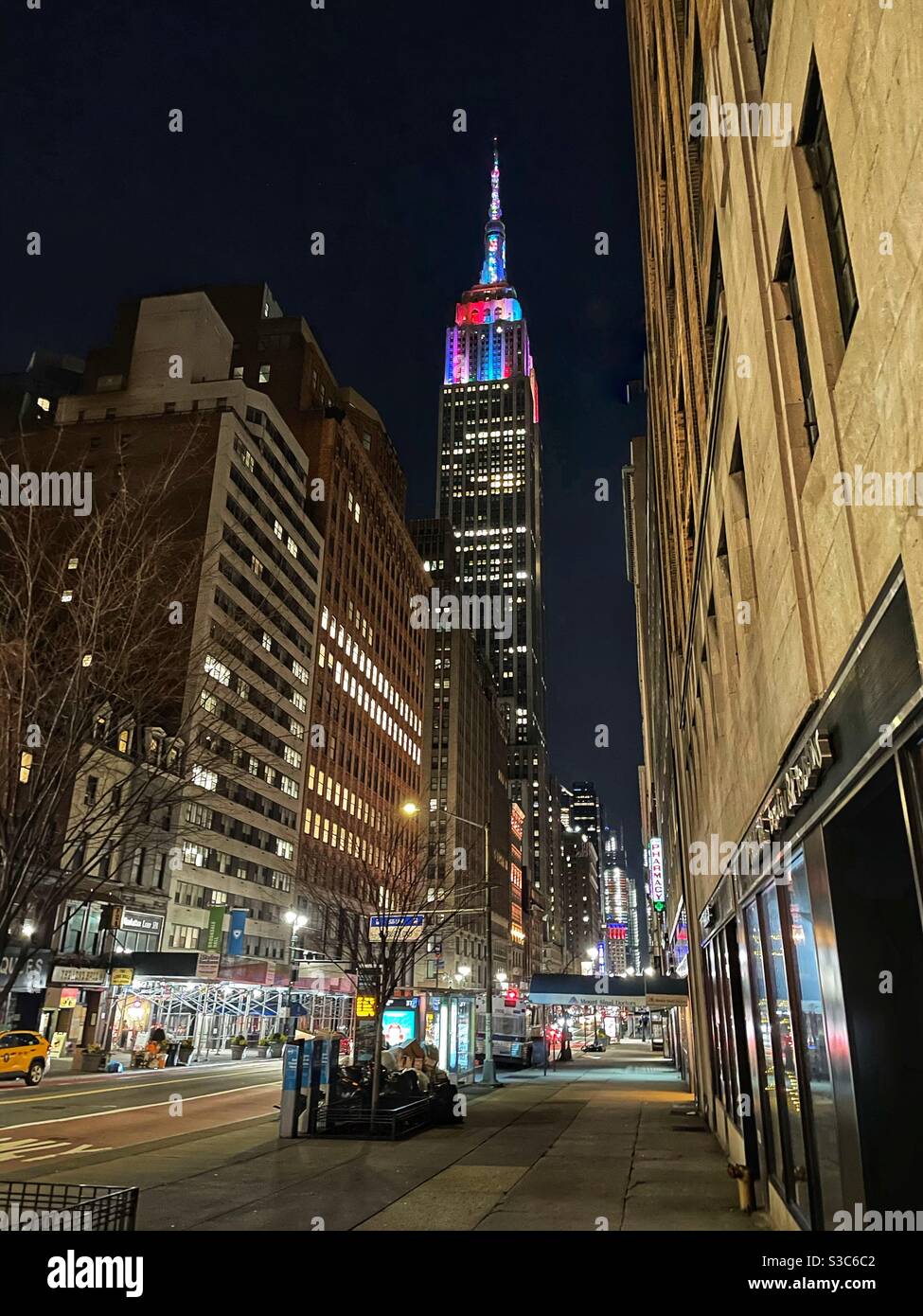 A bustling 34th St. near Park Avenue on New Year’s eve with the colorful lights of the Empire State building sparkling in the background in New York City, USA - Smartphone Captured Stock Image