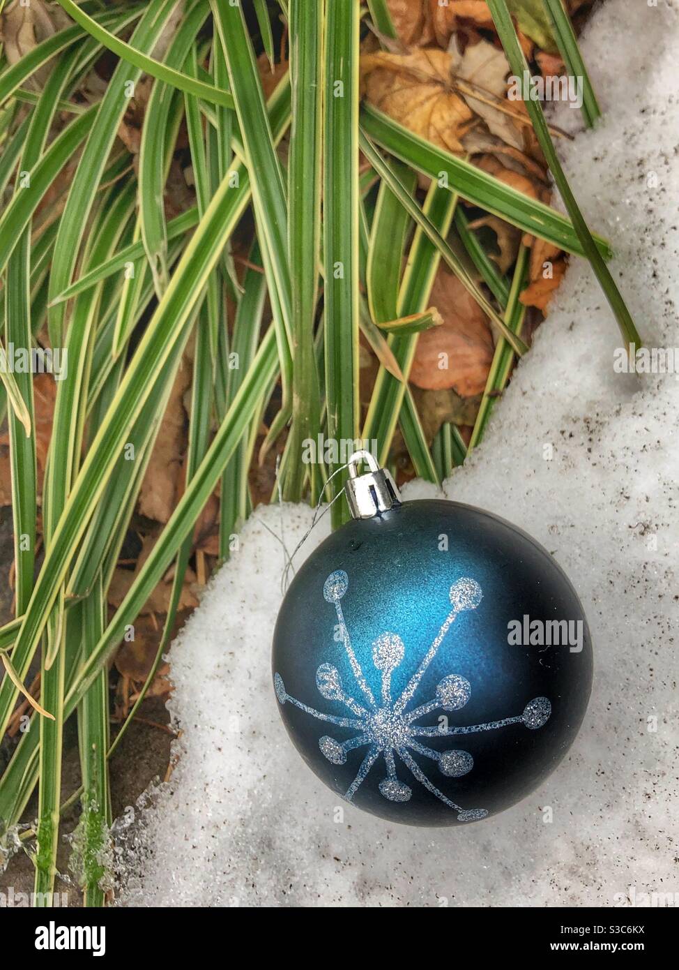 A blue Christmas ornament in the snow. - Smartphone Captured Stock Image