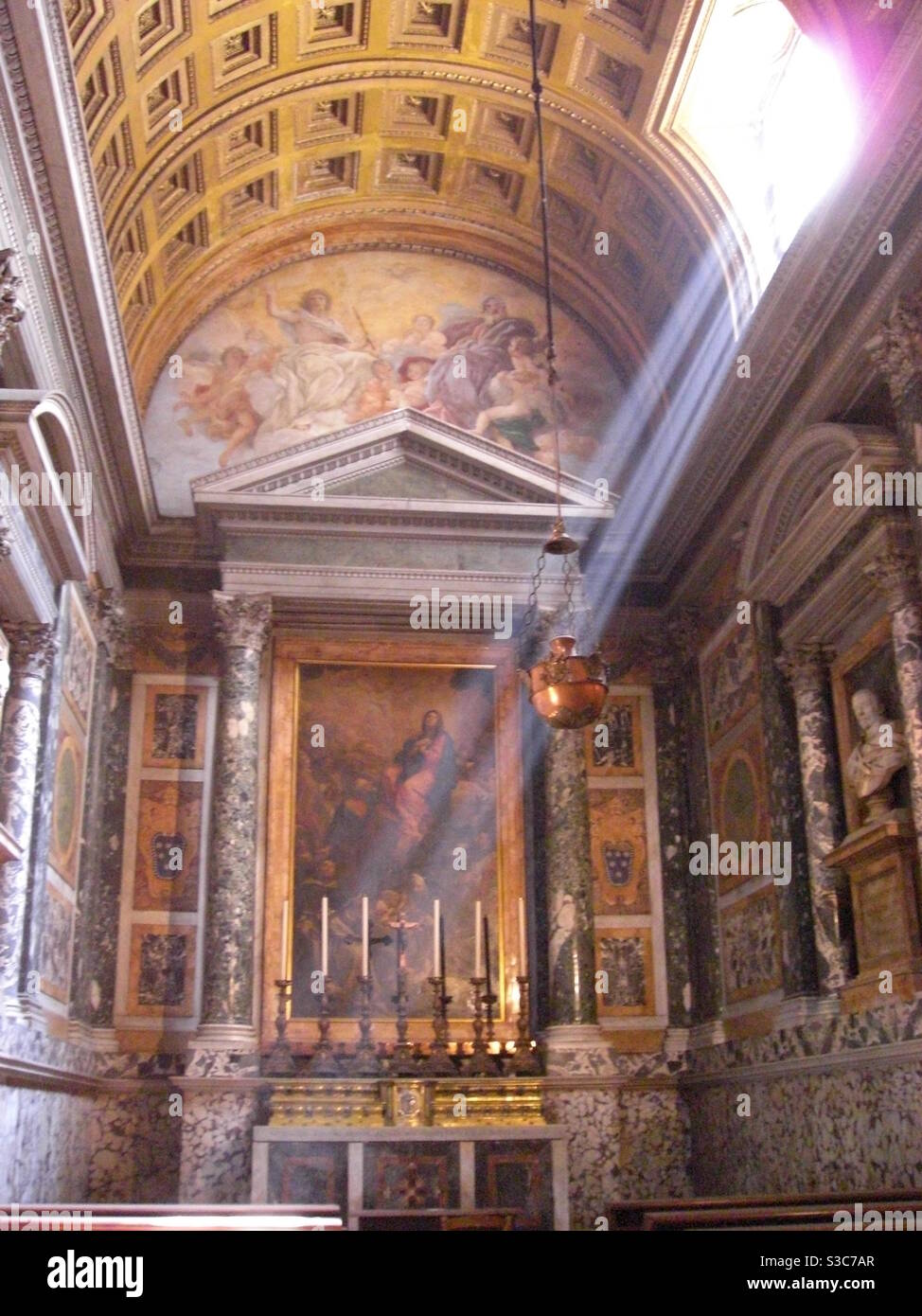 Beam of sunlight streaming through window into incense-filled beautiful catholic cathedral in Rome, Italy Stock Photo