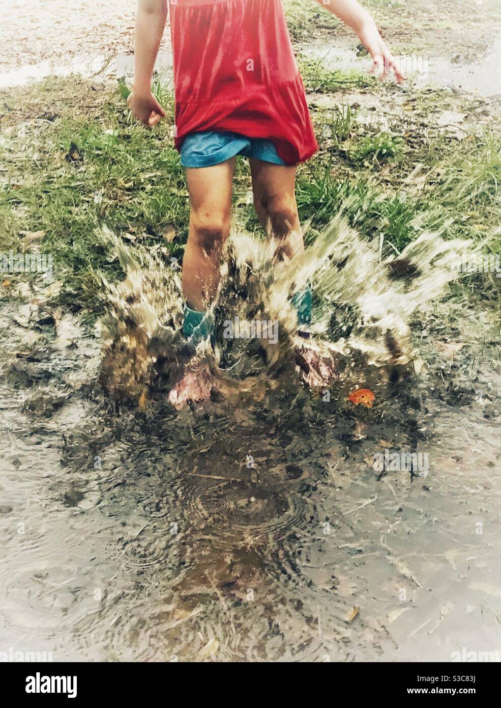 Preschooler puddle jumping in Southern November rain Stock Photo