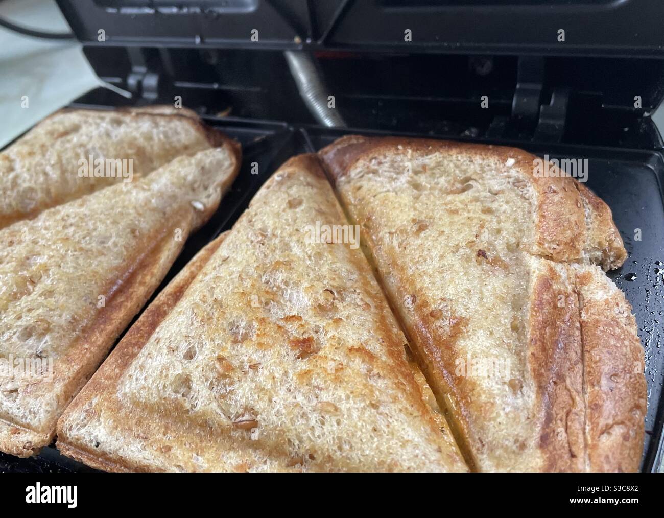 A classic toasted cheese sandwich being made in a toasted sandwich maker. Stock Photo