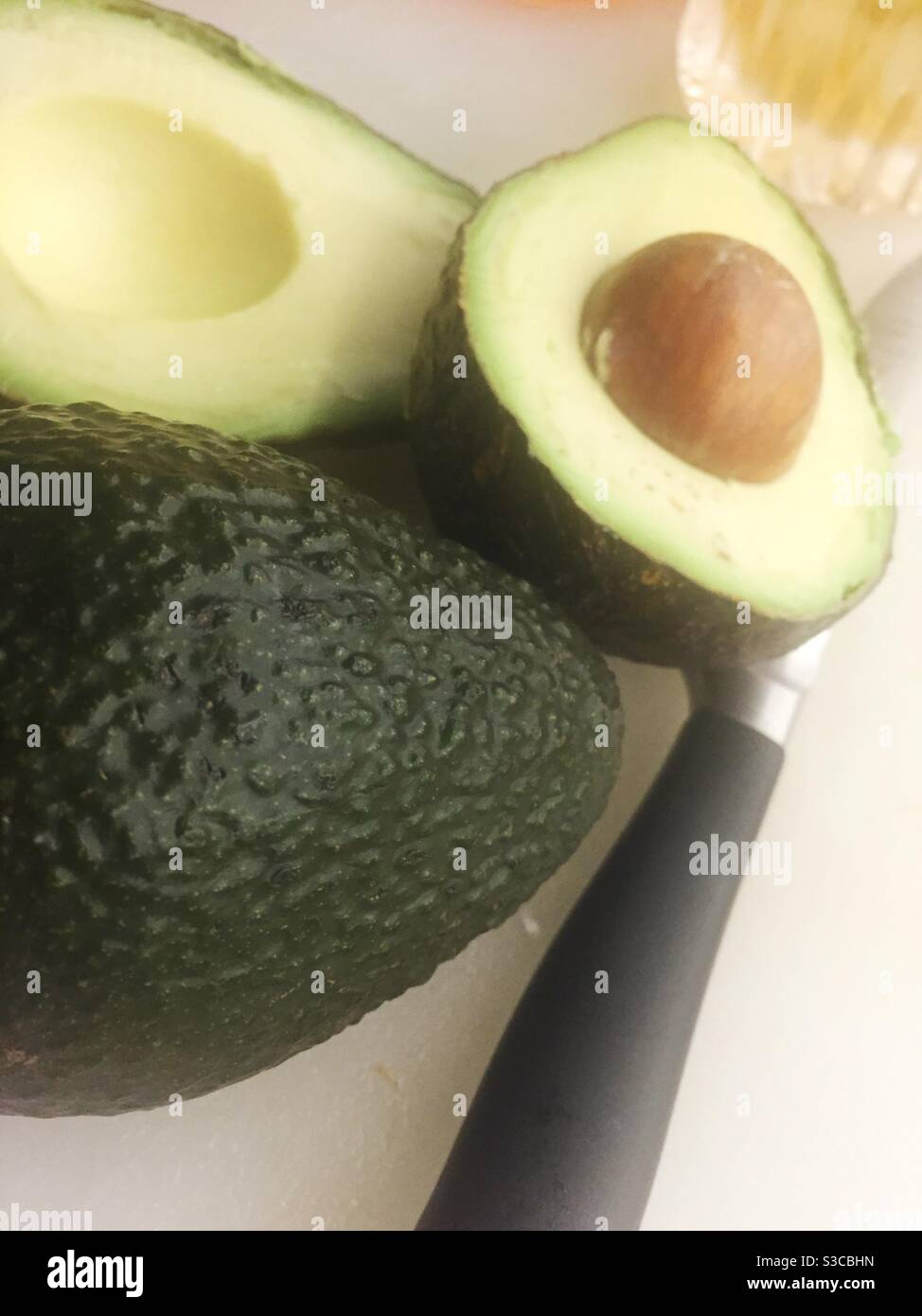 Two avocados on a cutting board with a knife - Smartphone Captured Stock Image