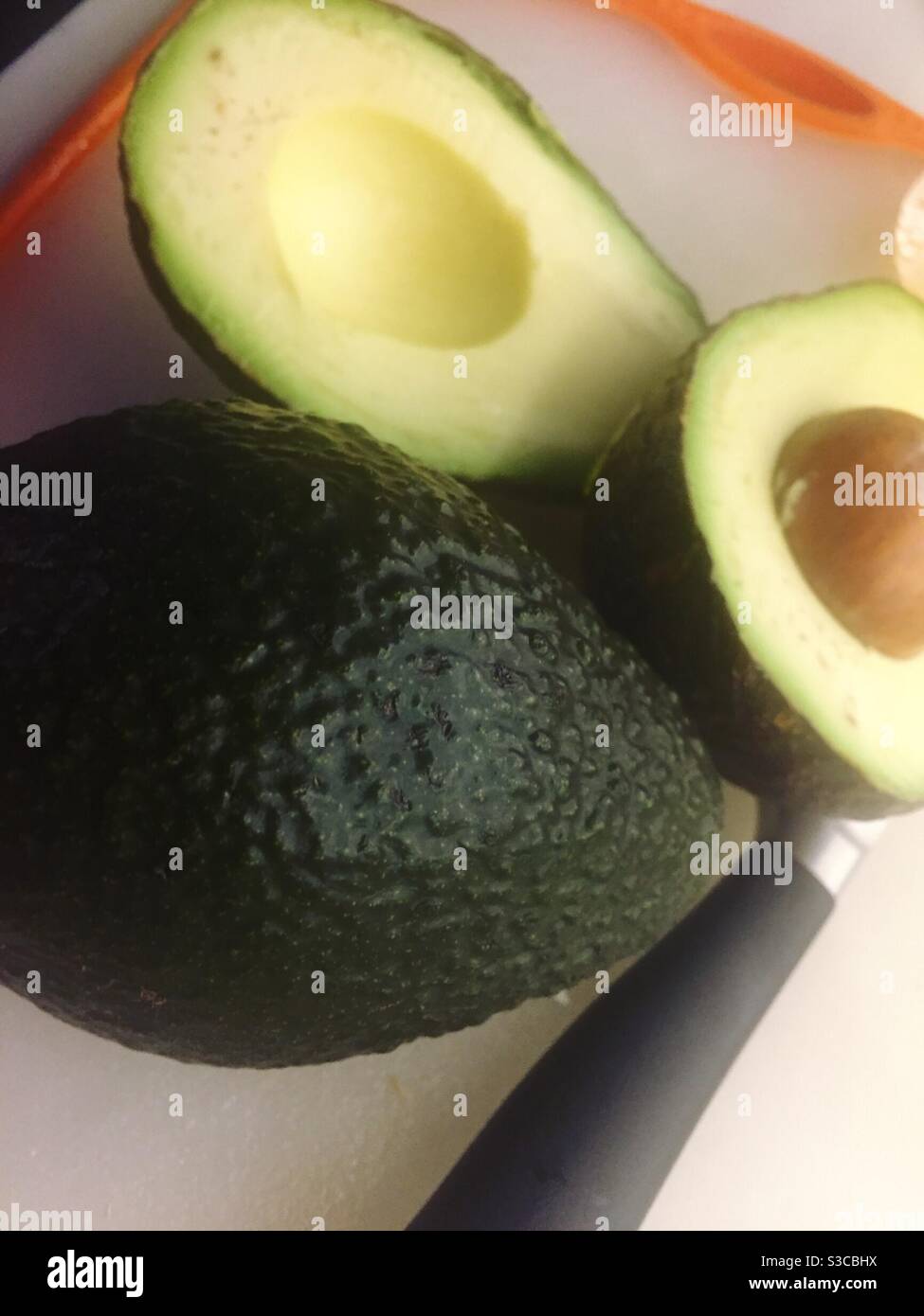 Fresh avocados on a cutting board with a knife - Smartphone Captured Stock Image