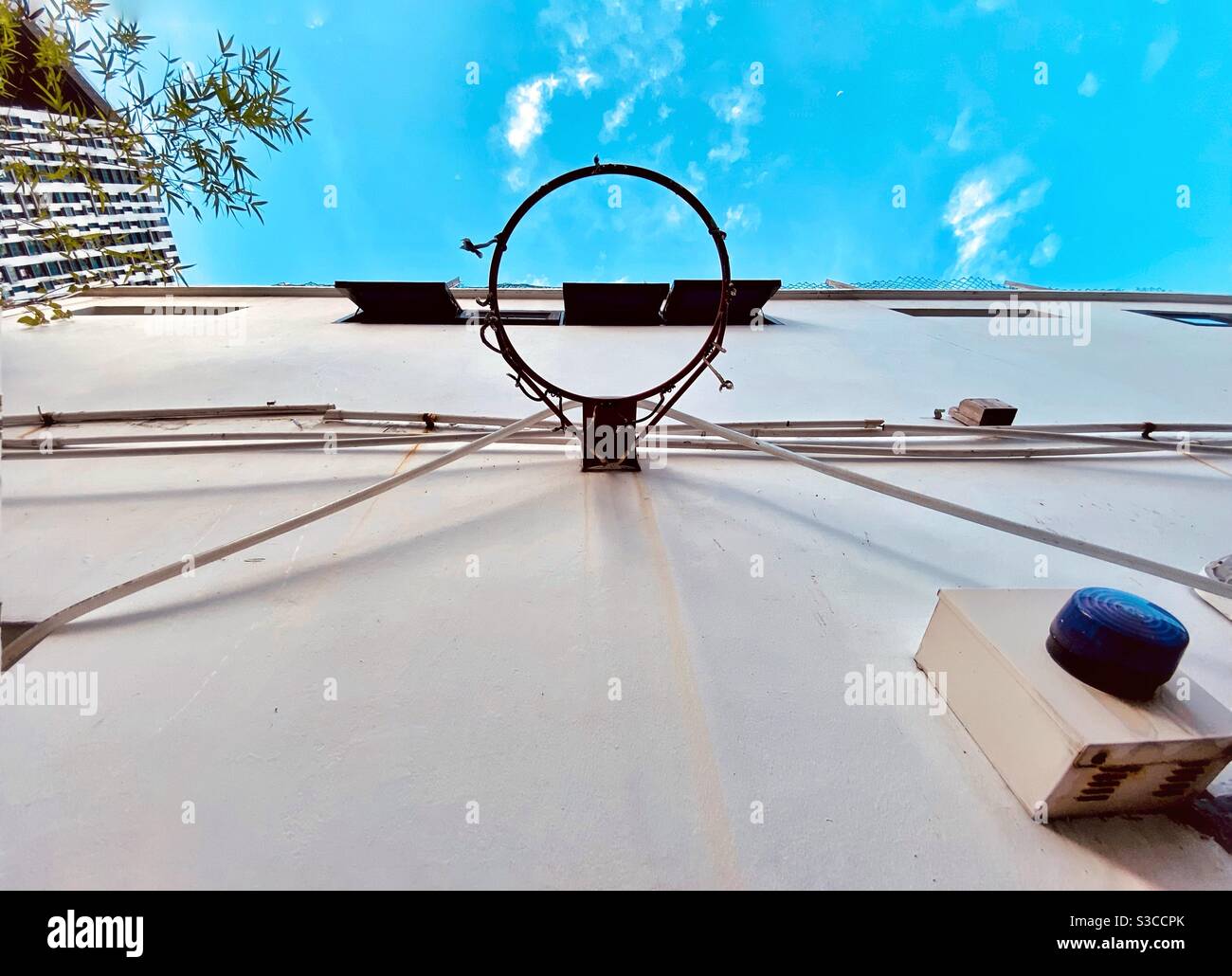 A worn out basketball hoop in a Singapore back alley on a clear sky day Stock Photo
