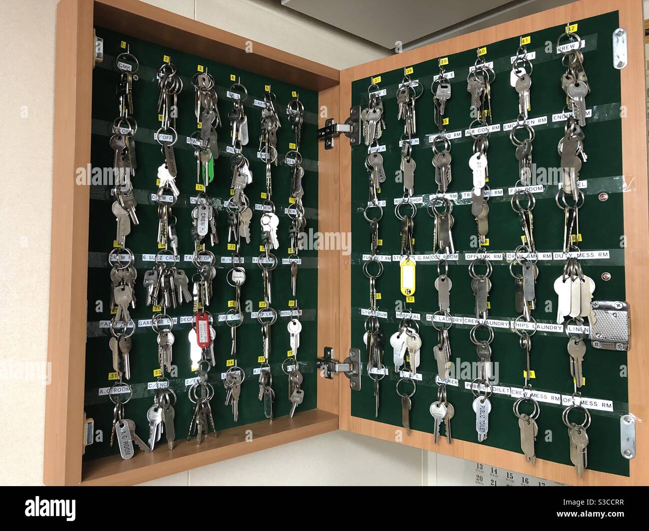 Keys from cabins, rooms and lockers hanging in wall cabinet. Stock Photo