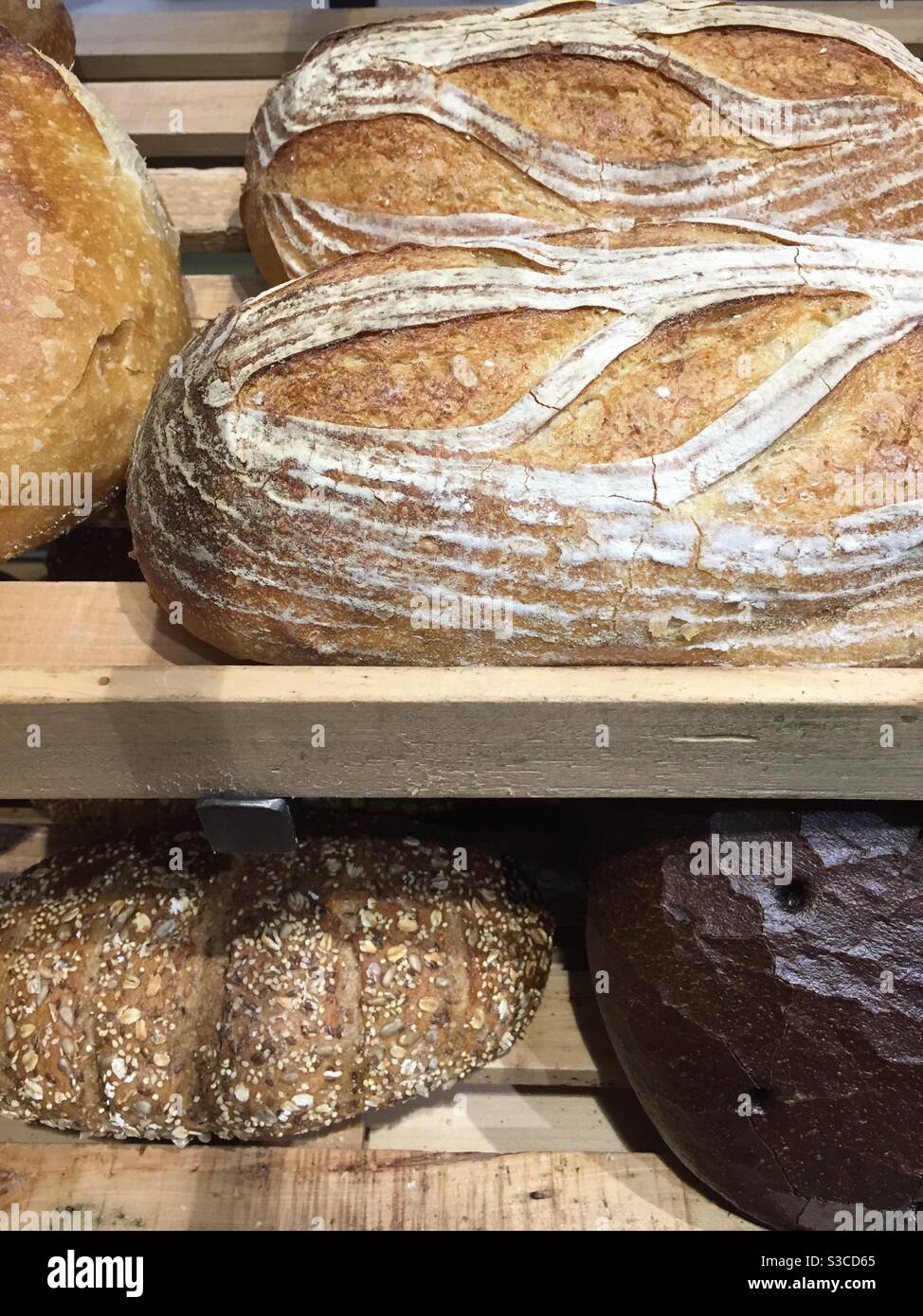 Handmade breads are displayed on a shelf in a grocery store bakery