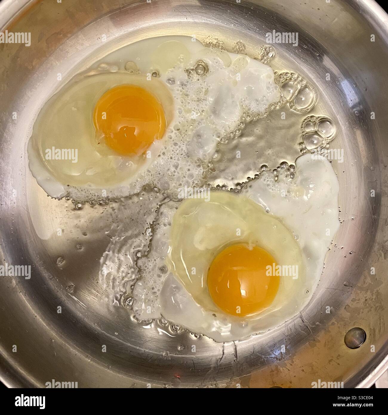 Overhead view of two eggs cooking in a stainless steel frying pan - Smartphone Captured Stock Image