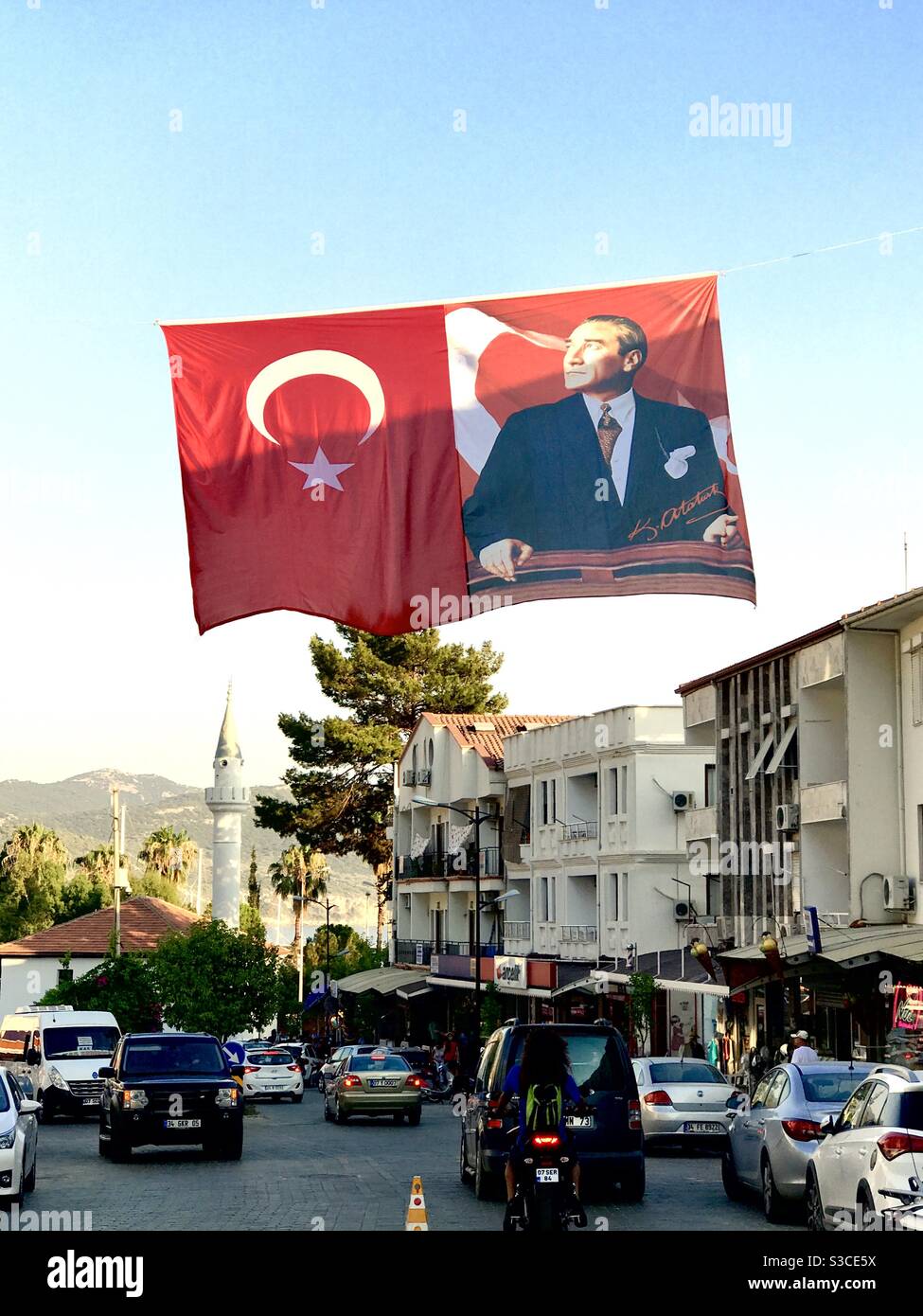 Turkish flag and Ataturk flag hangs above the road with a minaret in the background, Kas, Turkey Stock Photo