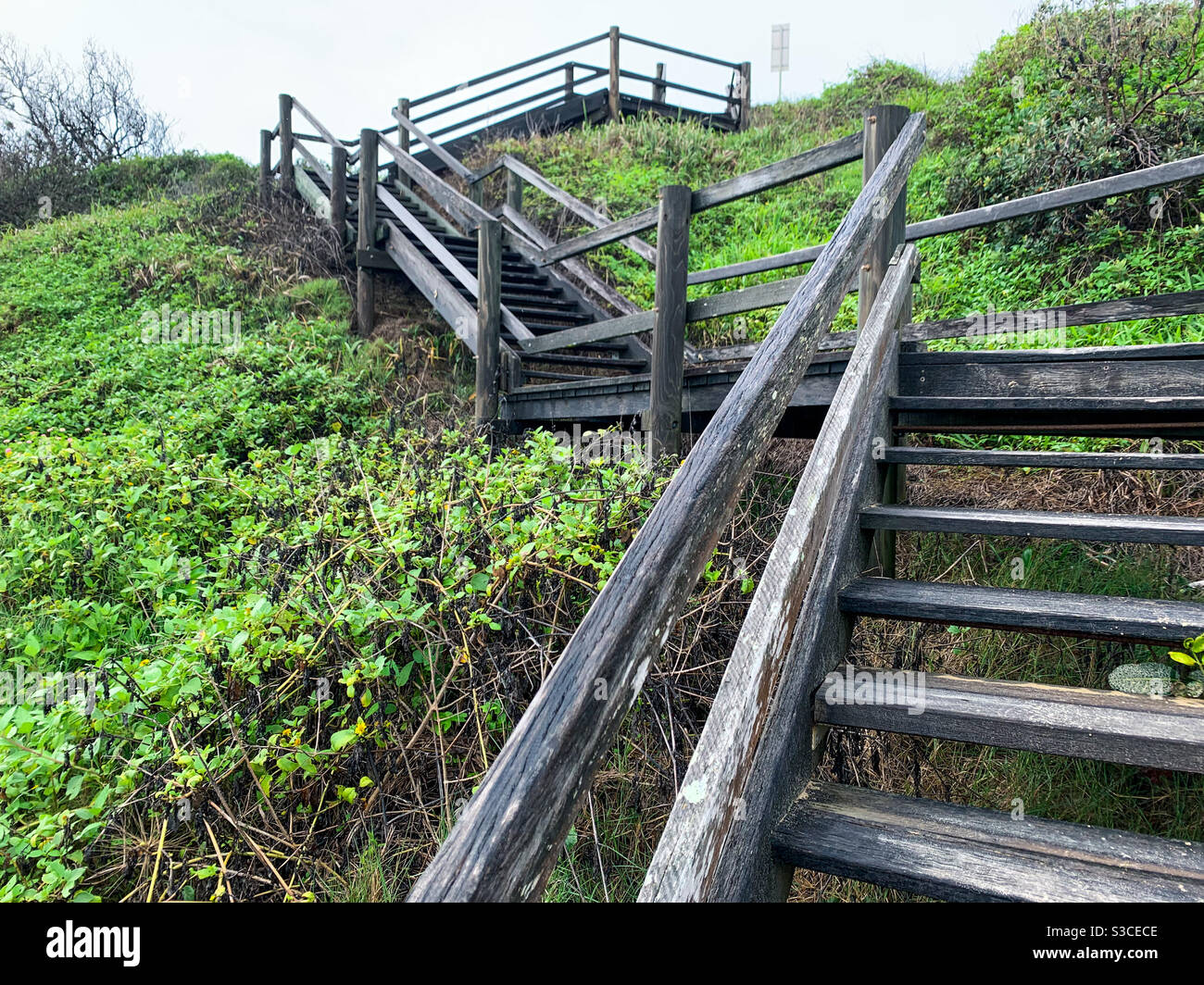 Stepping up. Wooden stairs leading from headland to beach Stock Photo