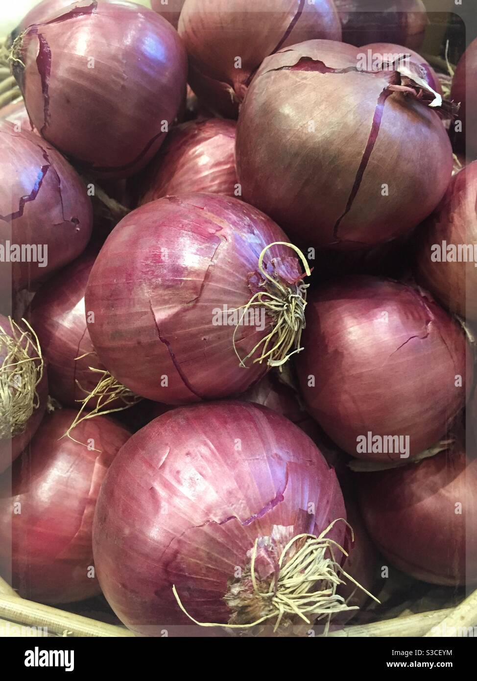 Basket of red onions for sale in the produce aisle of a supermarket, USA - Smartphone Captured Stock Image