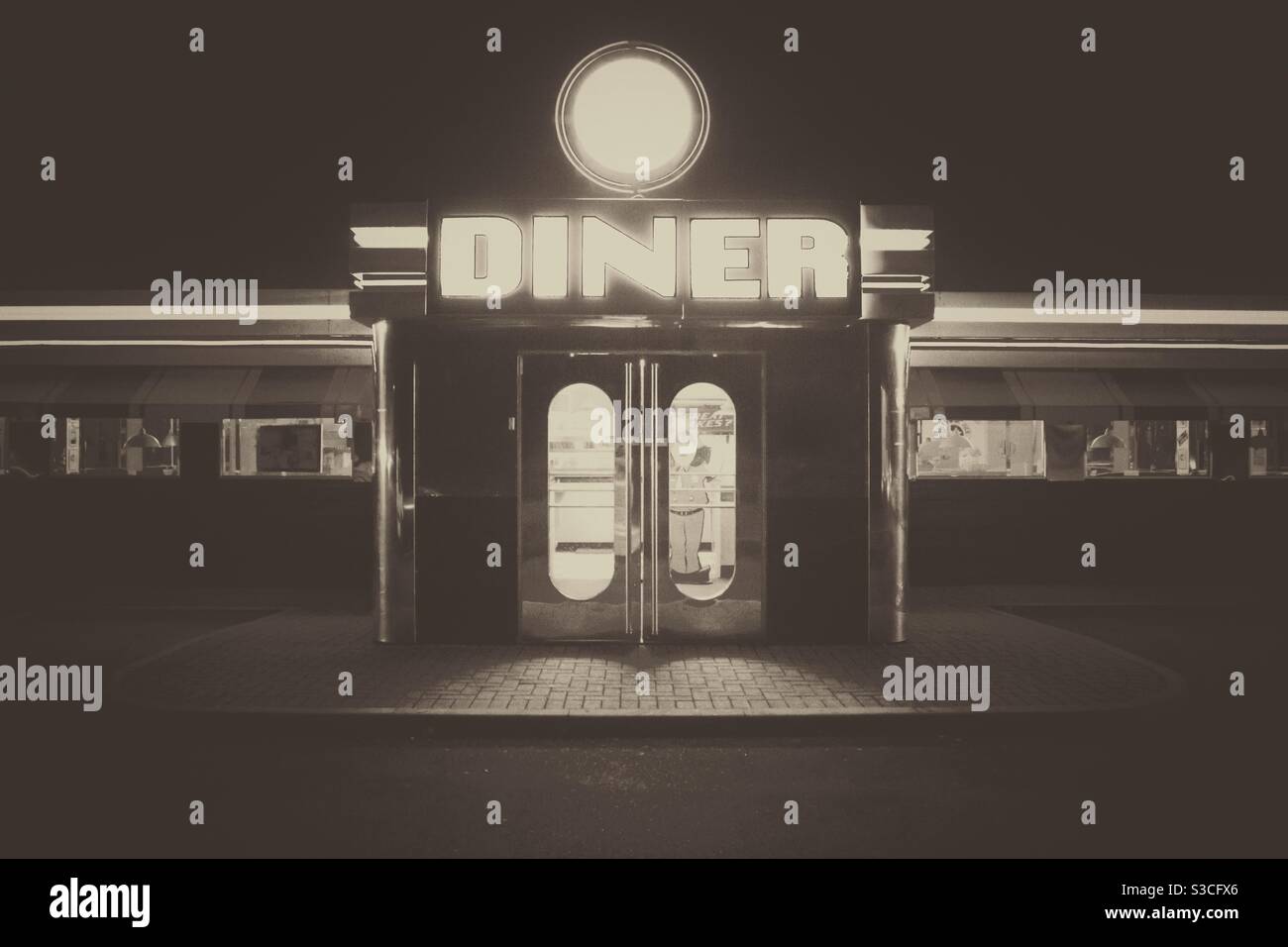 An old-fashioned American diner in black-and-white with bright lights at night Stock Photo