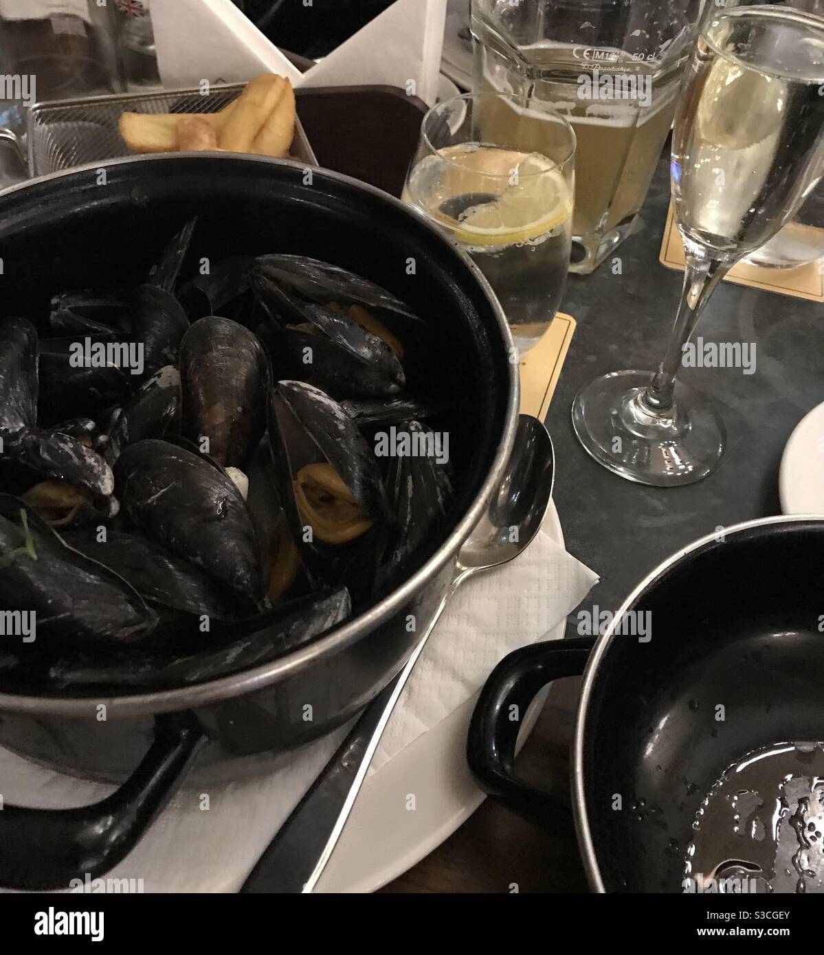 A pot of moules marinières mussels cooked in white wine served with French fries - Smartphone Captured Stock Image