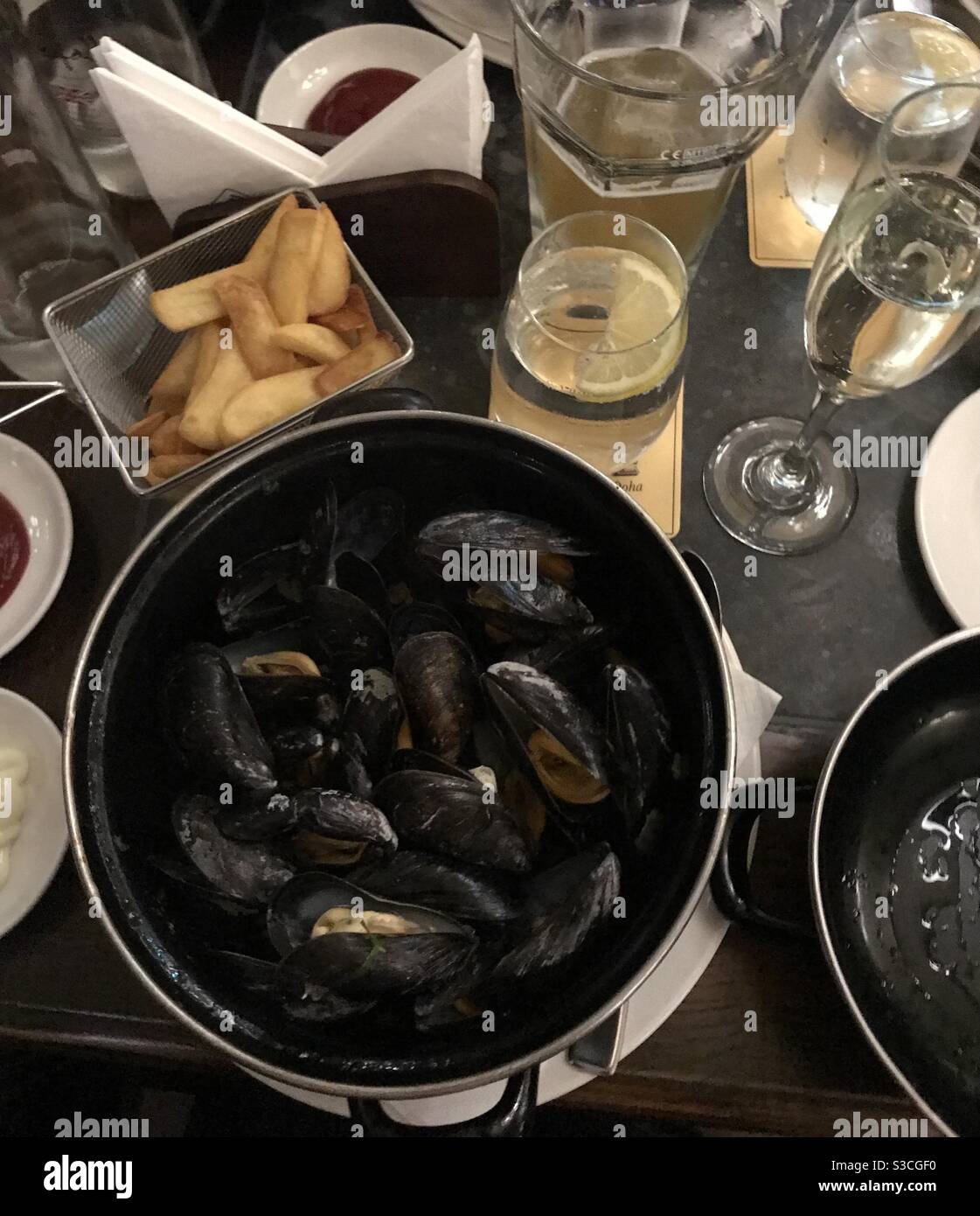 A pot of moules marinières mussels cooked in white wine served with French fries - Smartphone Captured Stock Image
